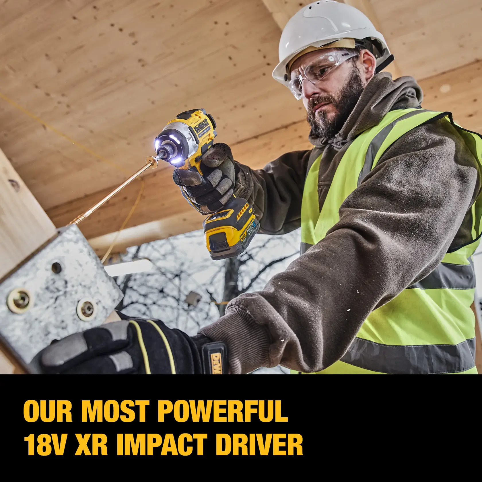Worker in safety gear uses a DEWALT power tool to drill into wood at a construction site.
