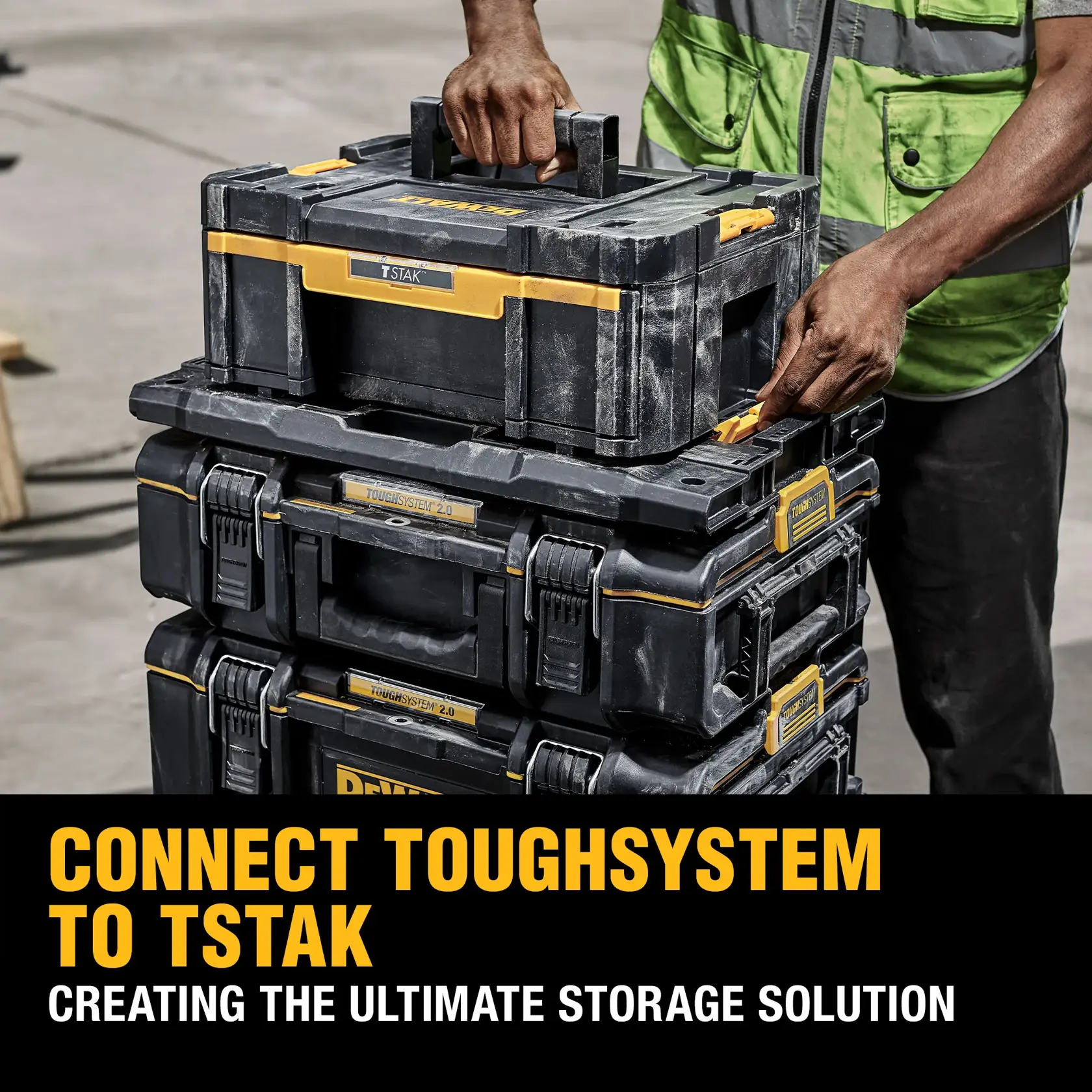 A person wearing a high-visibility vest uses a wheeled cart to transport stacked DEWALT tool boxes on a construction site.