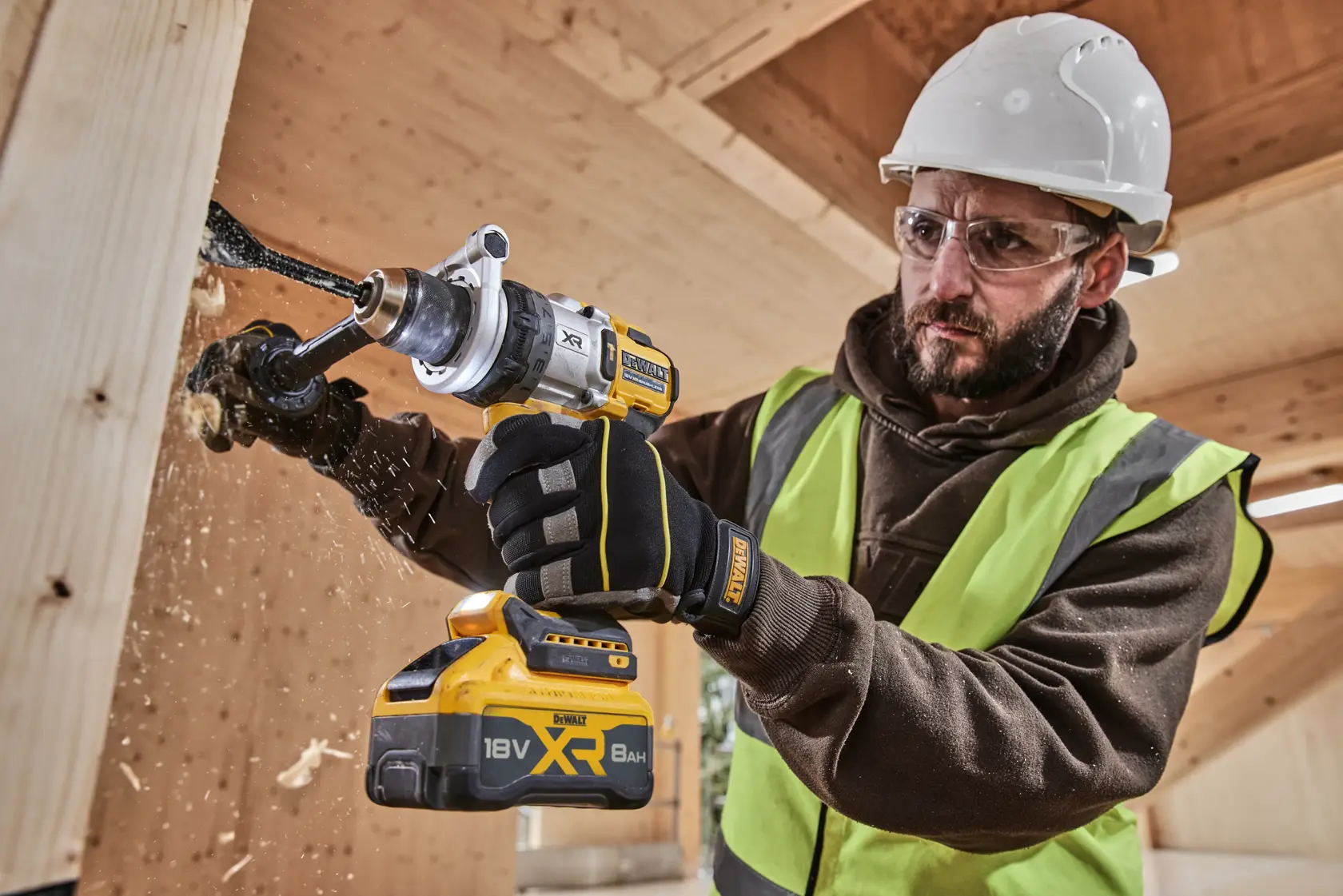Persona perfora madera con taladro inalámbrico DEWALT XR 18V 8Ah y usa equipo de seguridad.