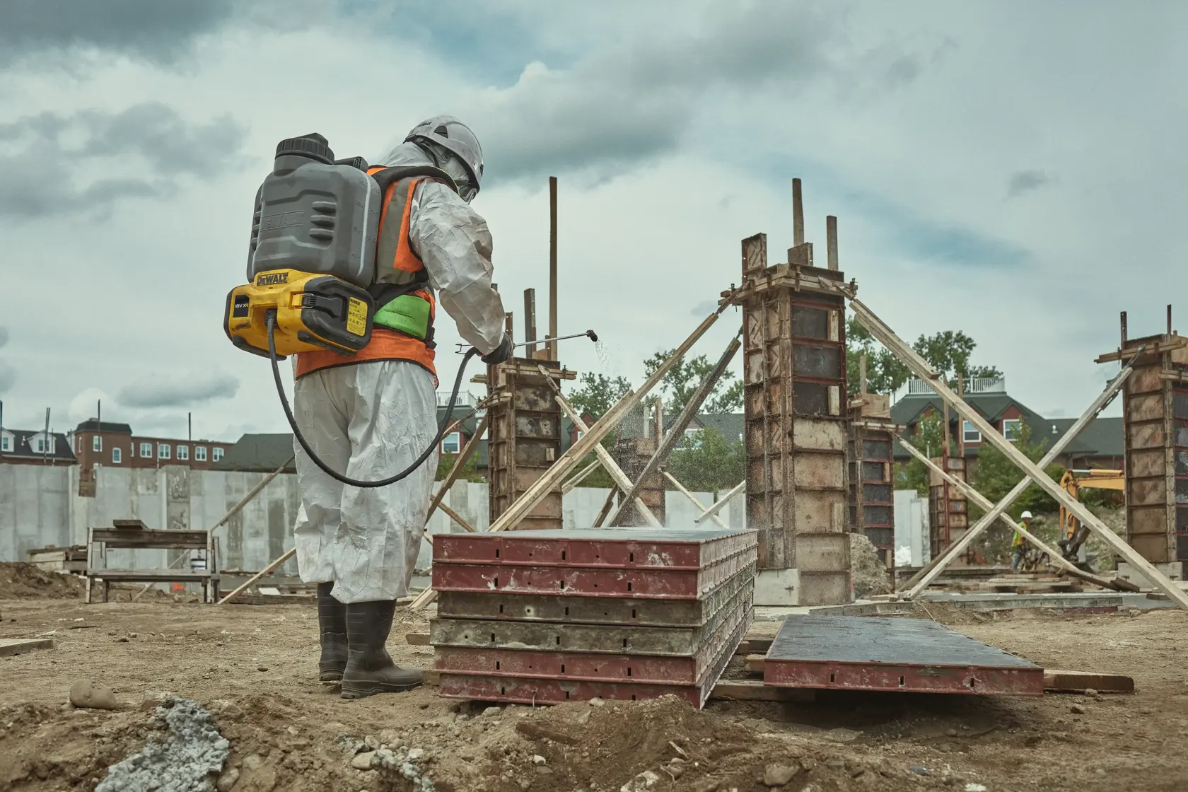Worker with DEWALT DCCS1100N-XJ, DCCS1100N on construction site, wearing safety gear and spraying equipment.