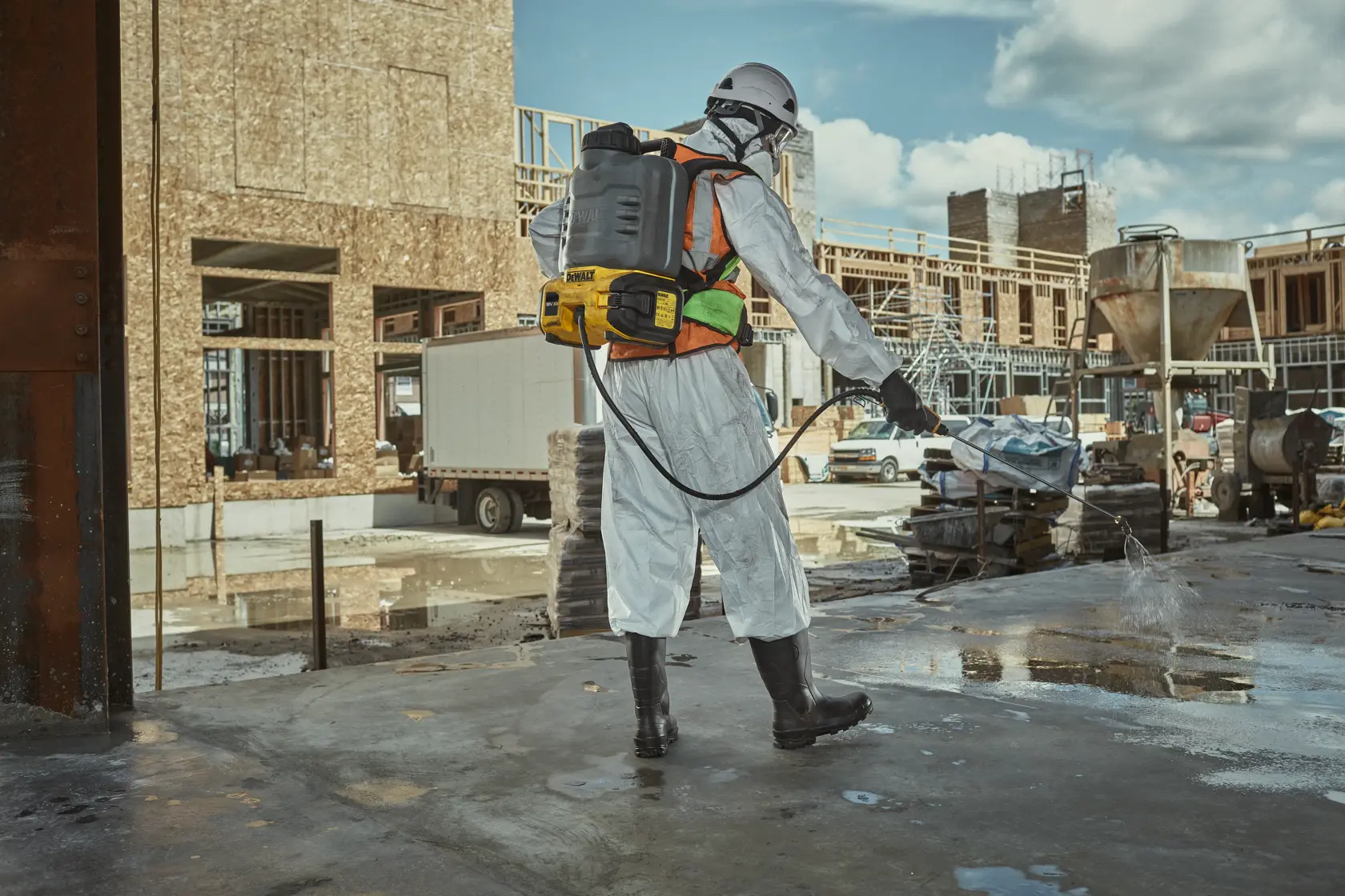 DEWALT DCCS1100N-XJ, DCCS1100N in use on construction site. Worker sprays surface, wearing full protective gear.