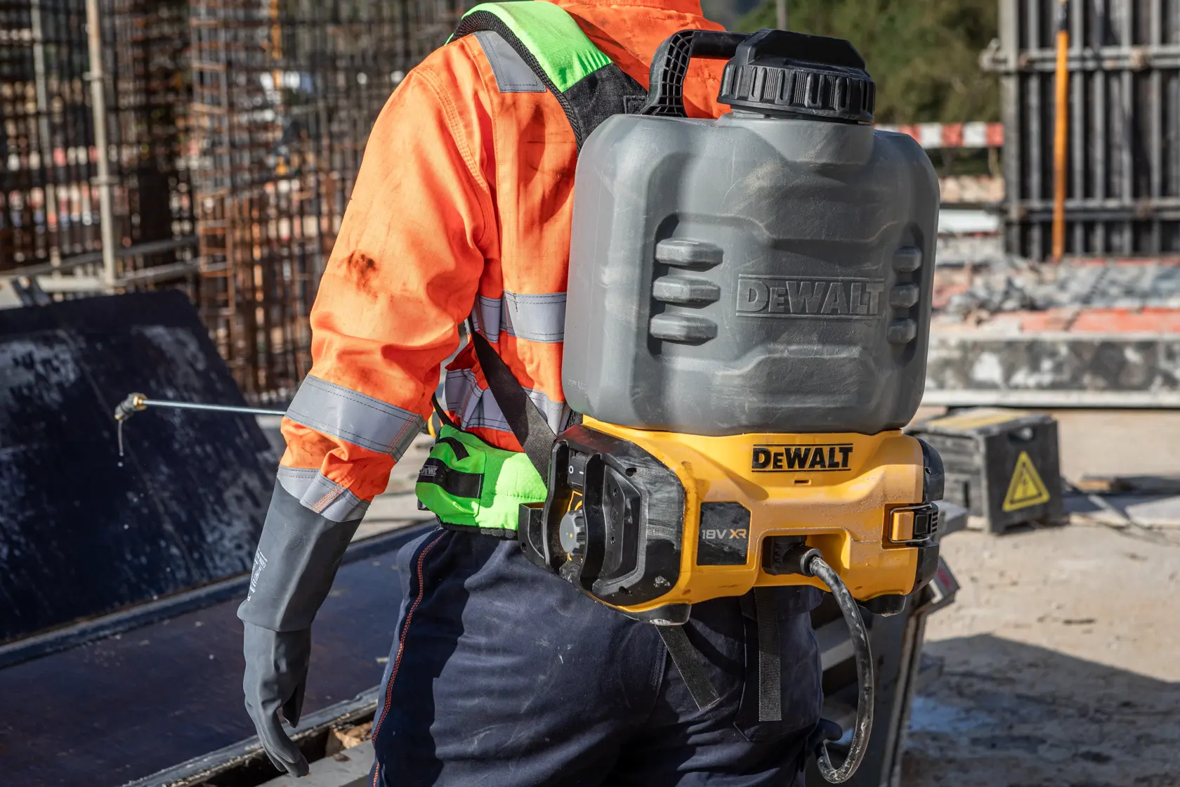 DEWALT sprayer worn on back. SKUs: DCCS1100N-XJ, DCCS1100N. Used outdoors, worker in hi-vis gear.
