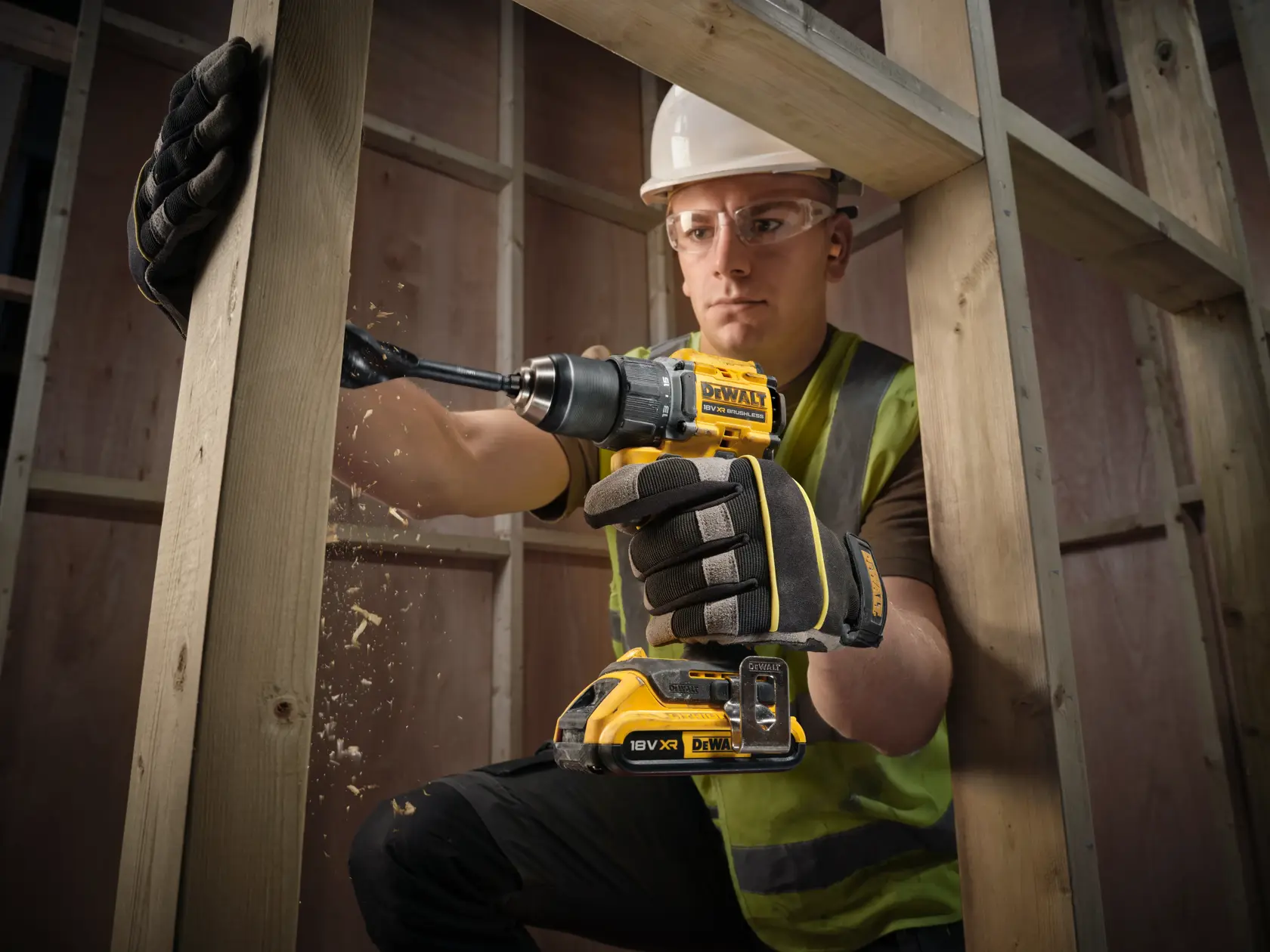DEWALT DCD794D2T-QW, DCD794D2T taladro en madera por persona con guantes y chaleco. Categoría fotografía.