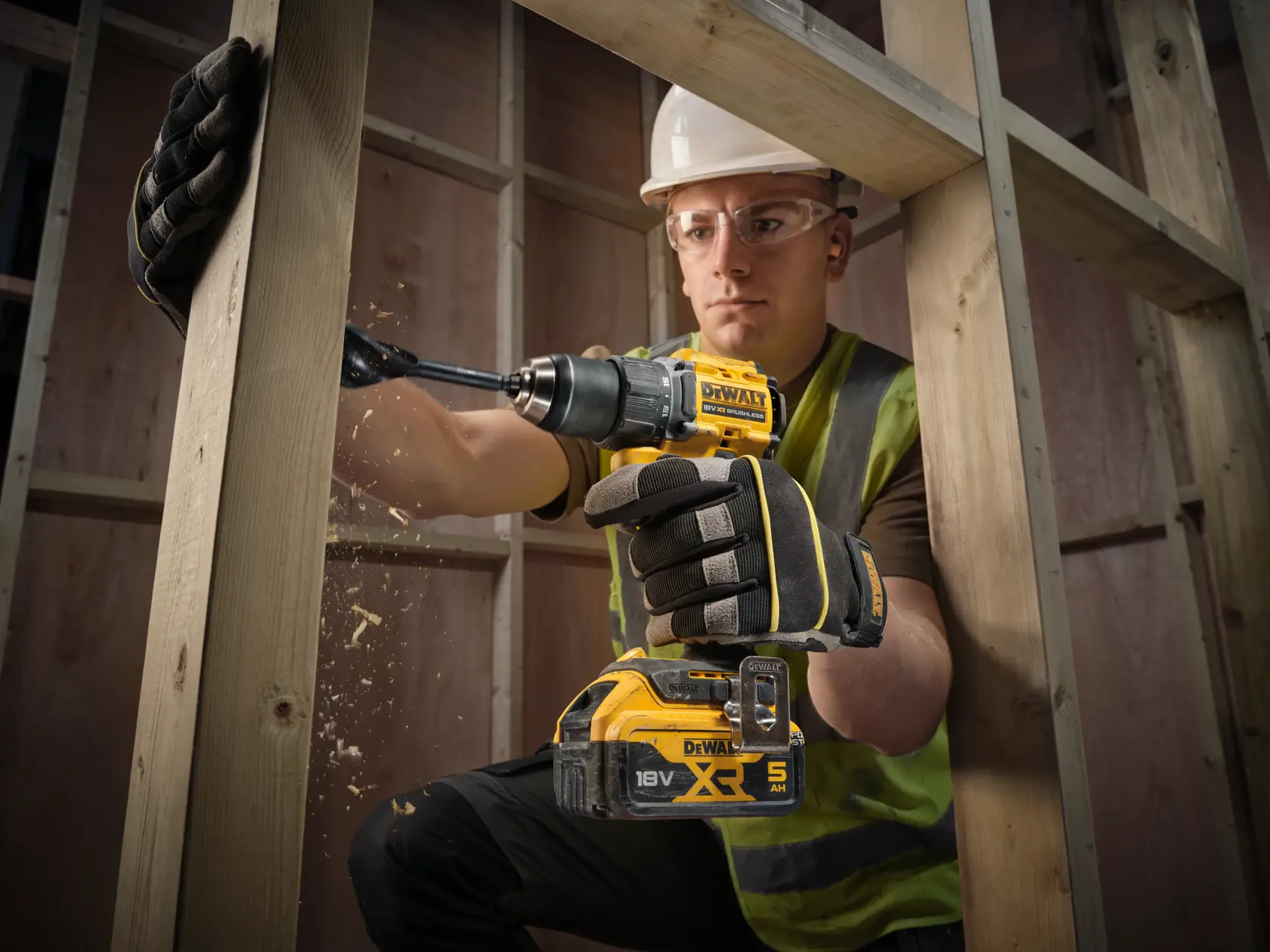Arbeiter bohrt Holz mit DEWALT DCD794NT, DCD794NT-XJ Akkugeräten auf Baustelle.