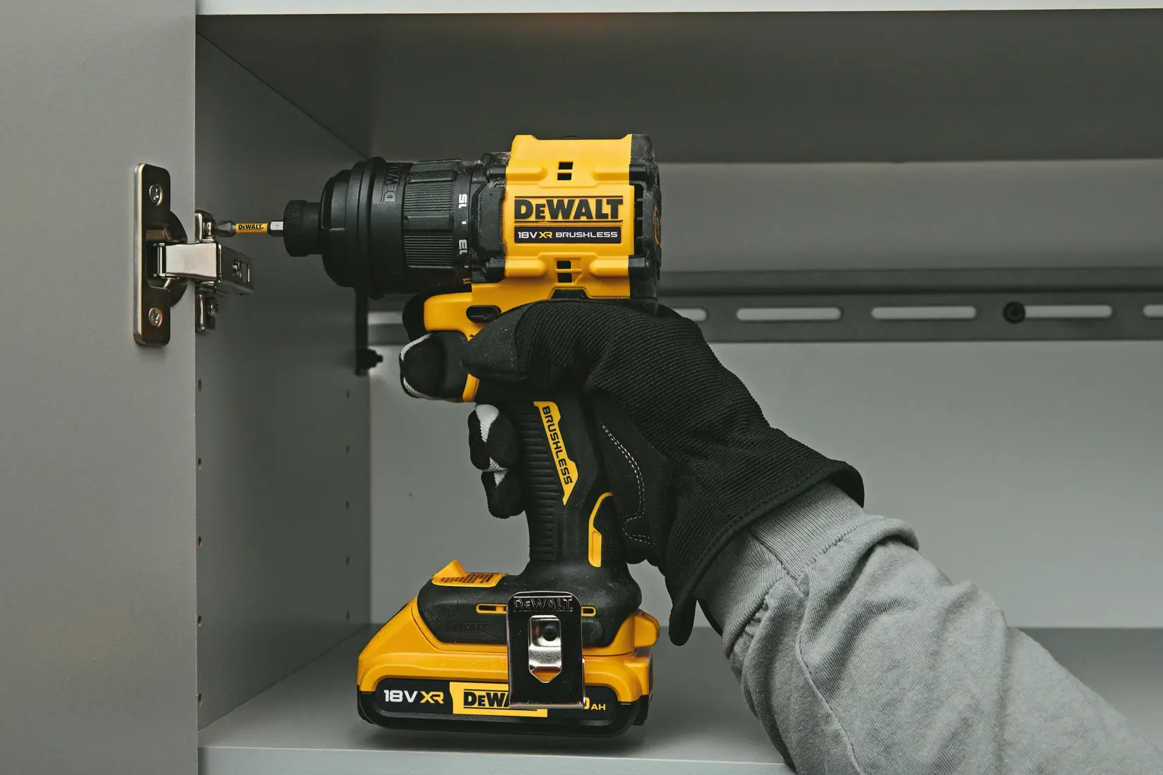 Furadeira DEWALT DCD803NT-XJ, DCD803NT usada em gabinete. Categoria fotografia. Mão com luva visível.