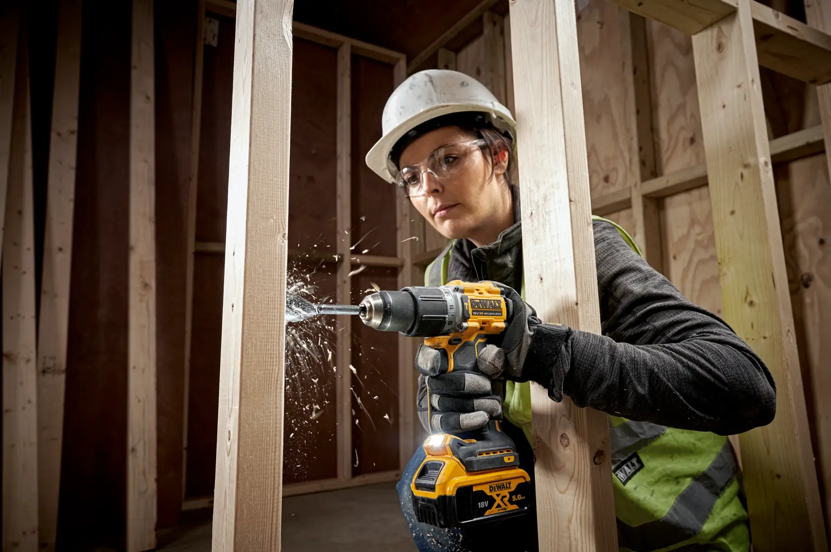 Persona usando taladro inalámbrico DEWALT para perforar vigas de madera en una obra.