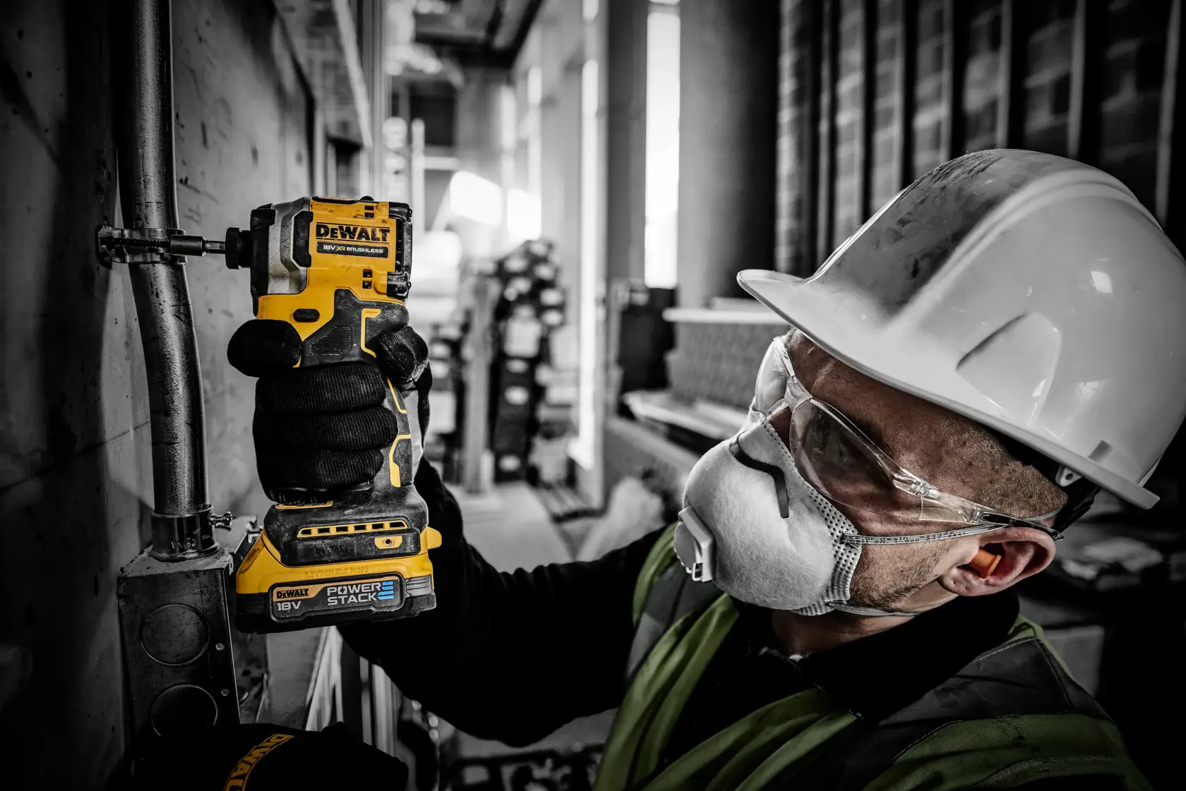 Trabajador usa taladro DEWALT DCF850E2T en tubo, con casco y protección en obra de construcción.