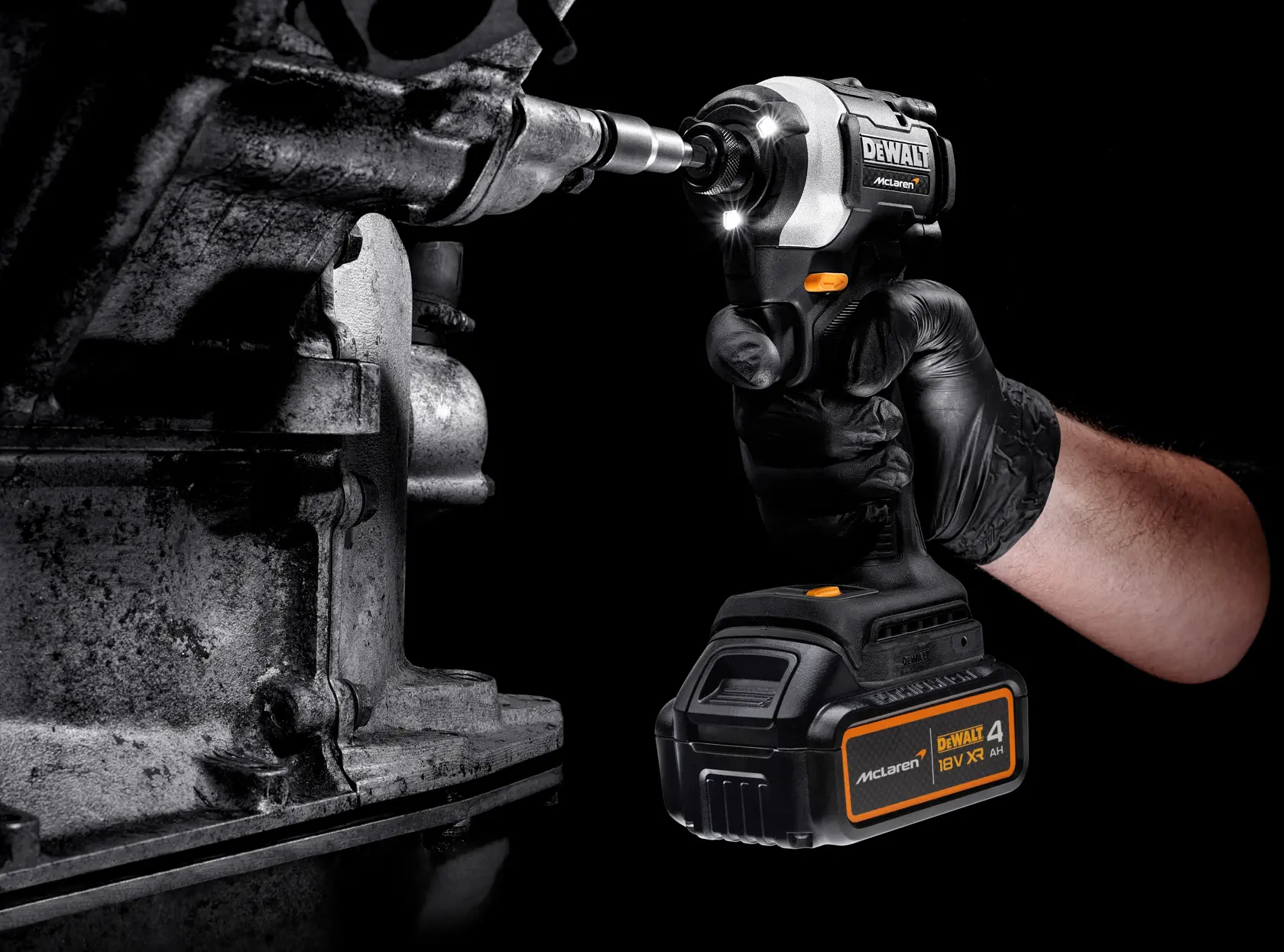 A gloved hand uses a DEWALT cordless impact wrench on a metal part. The tool is battery powered and illuminated.