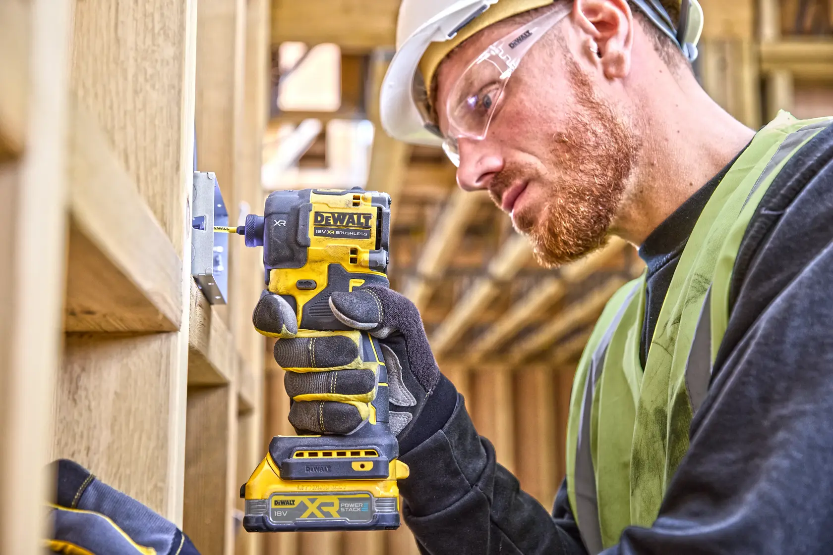 Trabajador usa DEWALT DCF870E2T en marco de madera con guantes, casco y chaleco de seguridad.