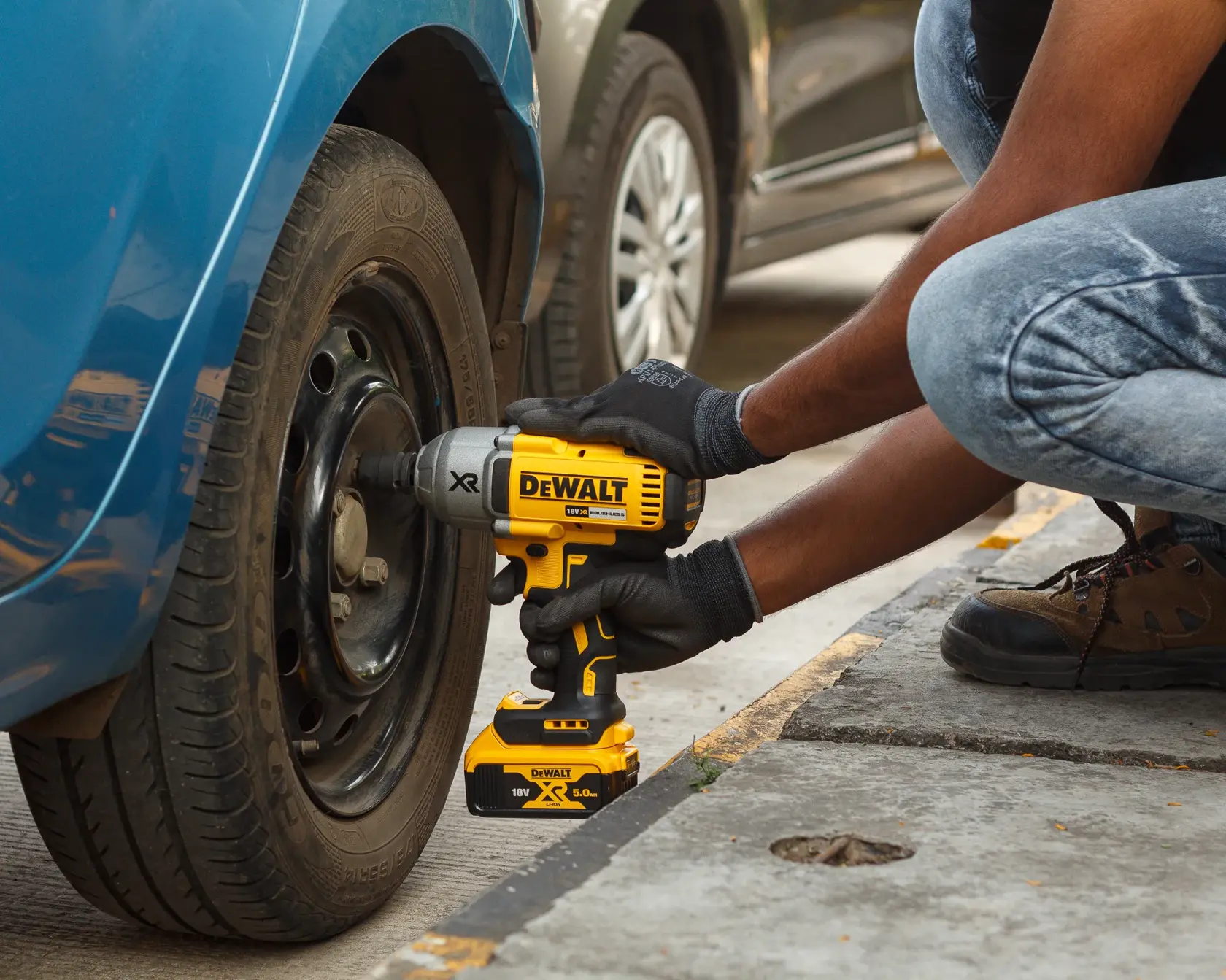 Une personne utilise une clé à chocs DEWALT sans fil pour serrer les boulons de roue.