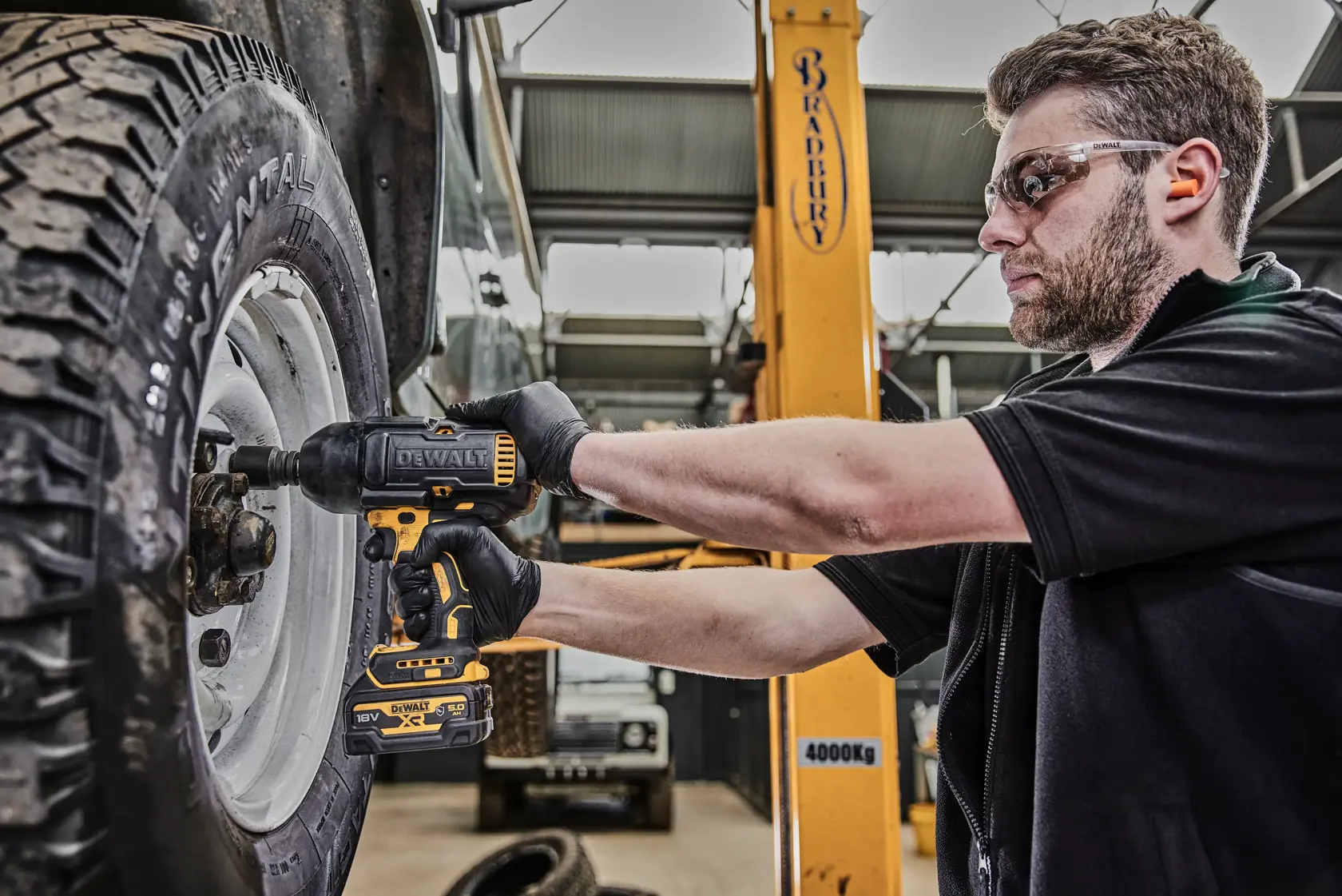 Person verwendet DEWALT DCF900P2G Schlagschrauber, um Radmuttern in einer Werkstatt zu befestigen.