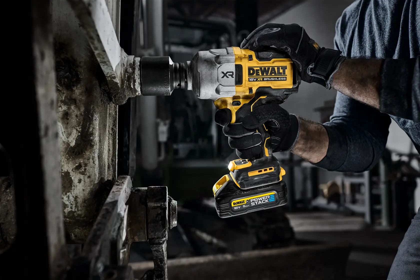 Mano usando llave de impacto inalámbrica DEWALT en maquinaria metálica de taller.