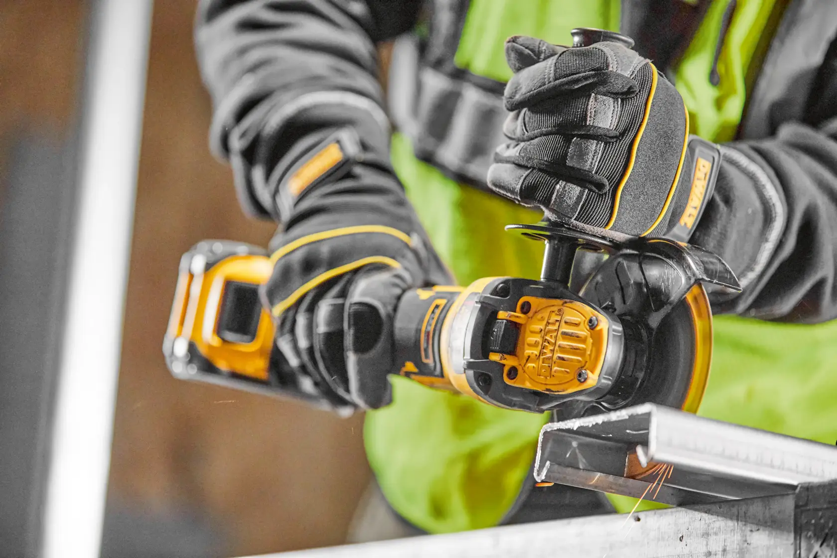 Arbeiter nutzt DEWALT Akku-Winkelschleifer zum Schneiden von Metall, mit Handschuhen und Schutzkleidung.