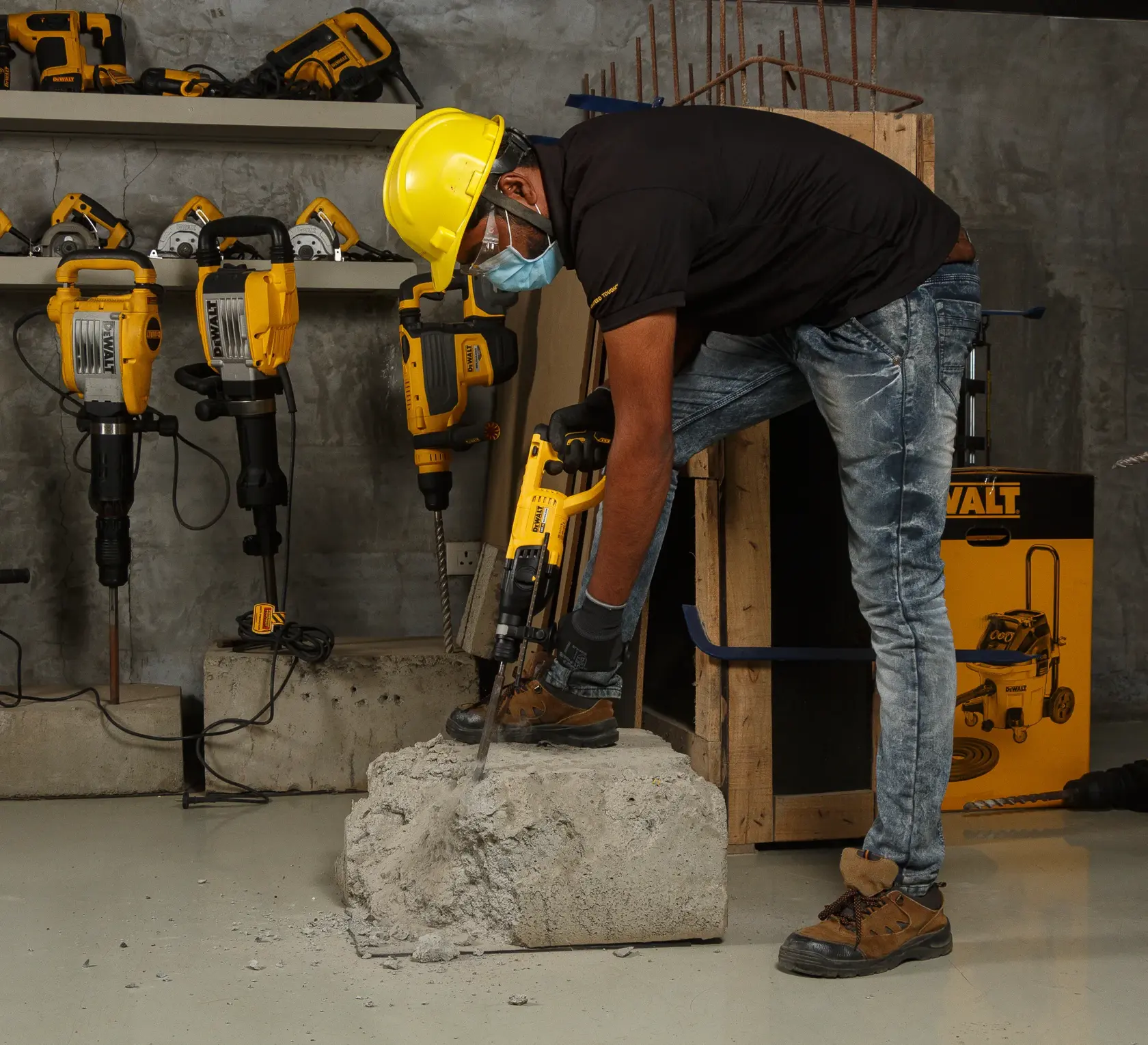 Arbeiter nutzt einen DEWALT Bohrhammer auf Beton, trägt Schutzkleidung. Weitere DEWALT Werkzeuge sind sichtbar.