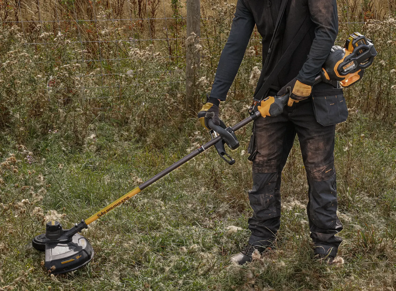 Persona usando desbrozadora inalámbrica DEWALT en césped al aire libre.