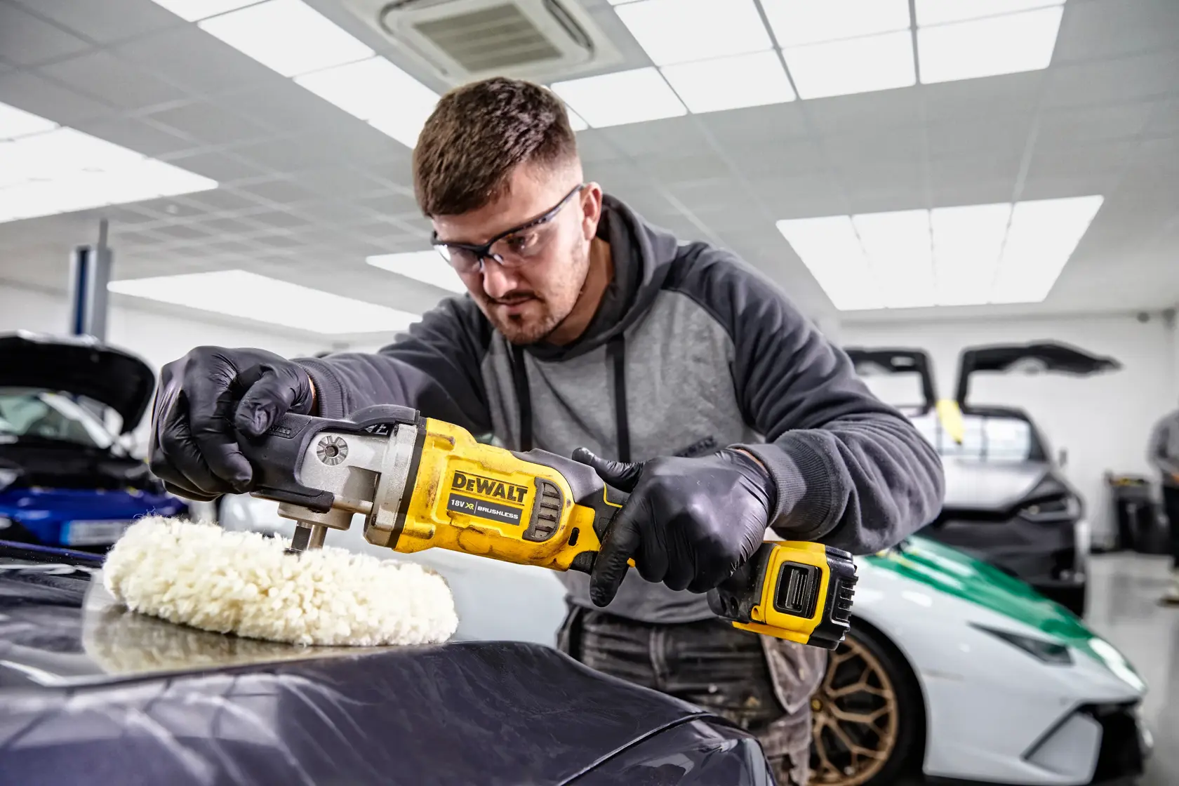 Persona pule el capó de un coche en garaje con pulidora inalámbrica DEWALT DCM849P2.