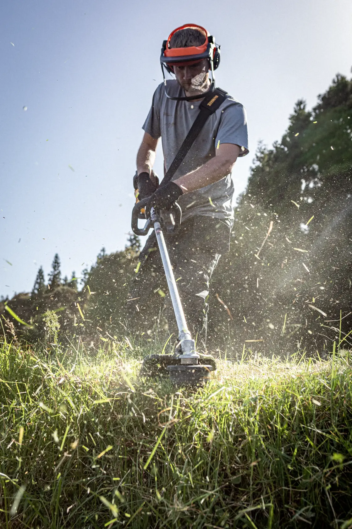 DEWALT brush cutter DCMST911N, DCMST911N-XJ used outdoors. Protective gear worn. Photography category.