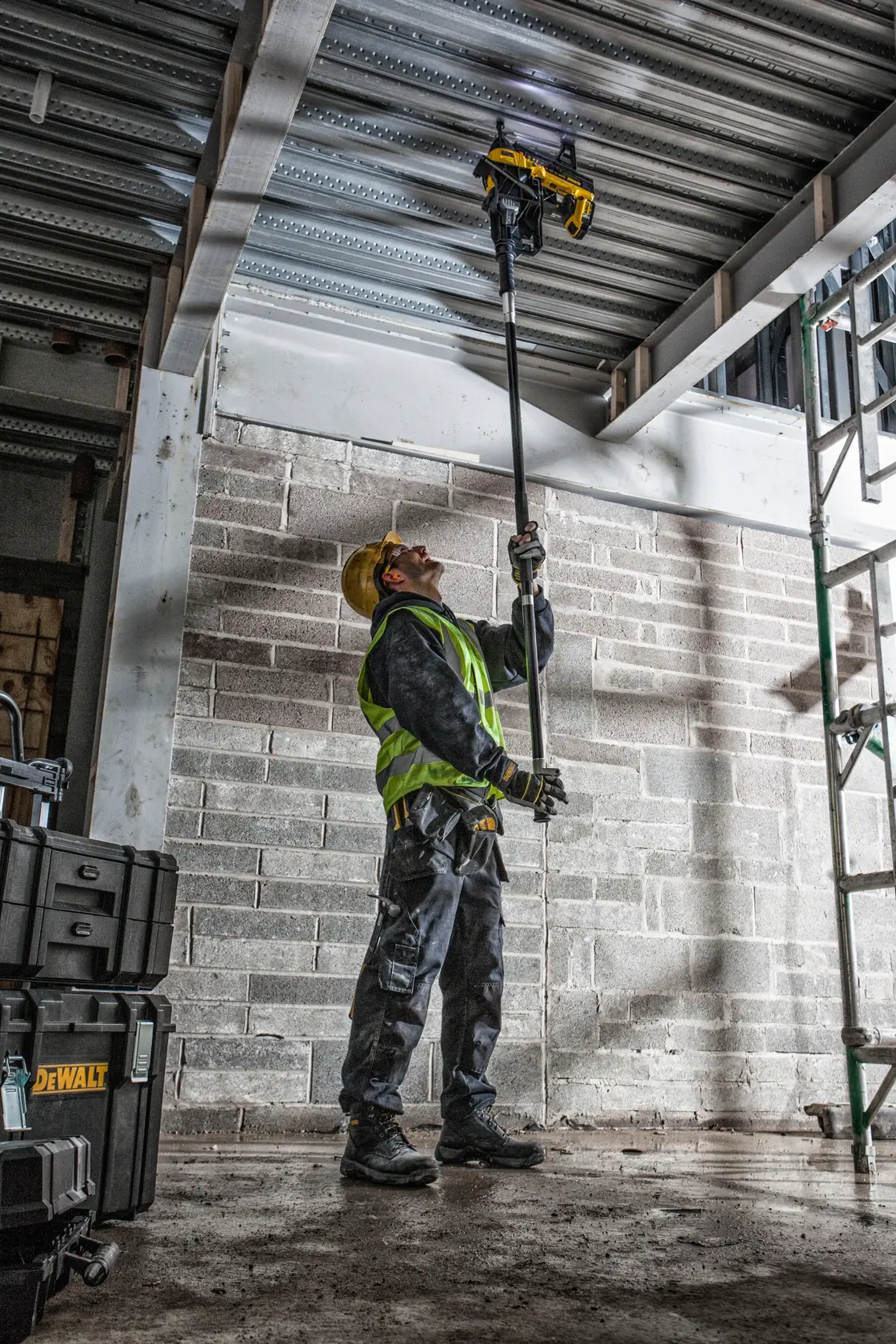 Trabajador usa DEWALT DCN890P2 sobre la cabeza en obra. Visible equipo de seguridad.