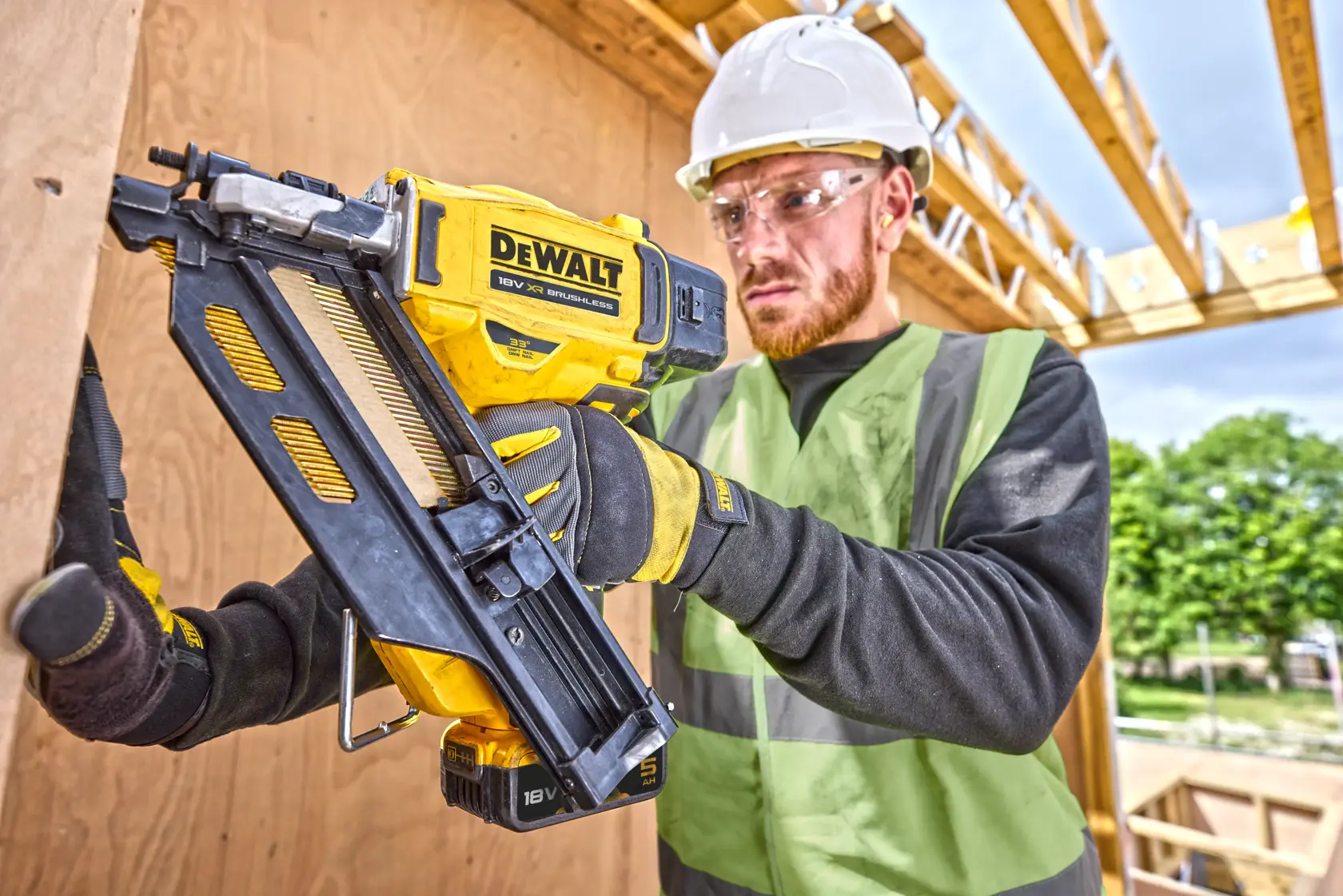 Clavadora DEWALT DCN930P2 usada por trabajador con equipo de seguridad en estructura de madera.
