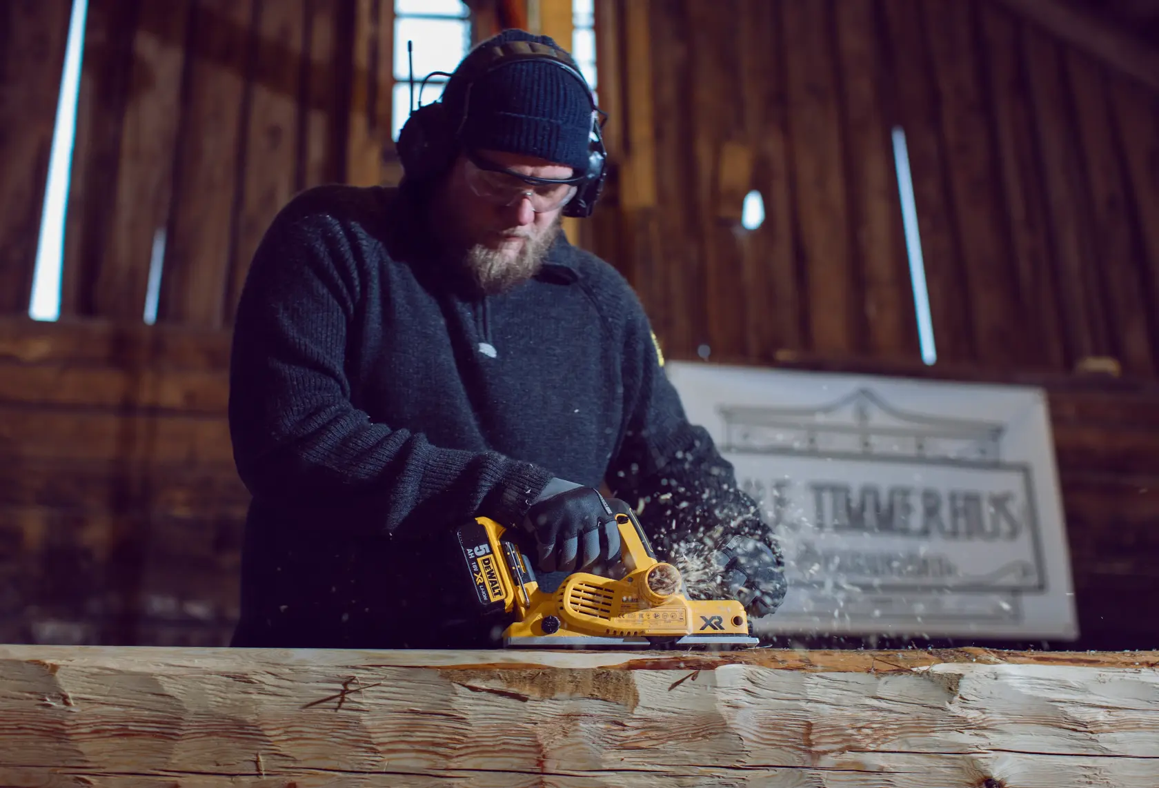 Persona usando una cepilladora DEWALT DCP580P2 en una viga de madera en taller.
