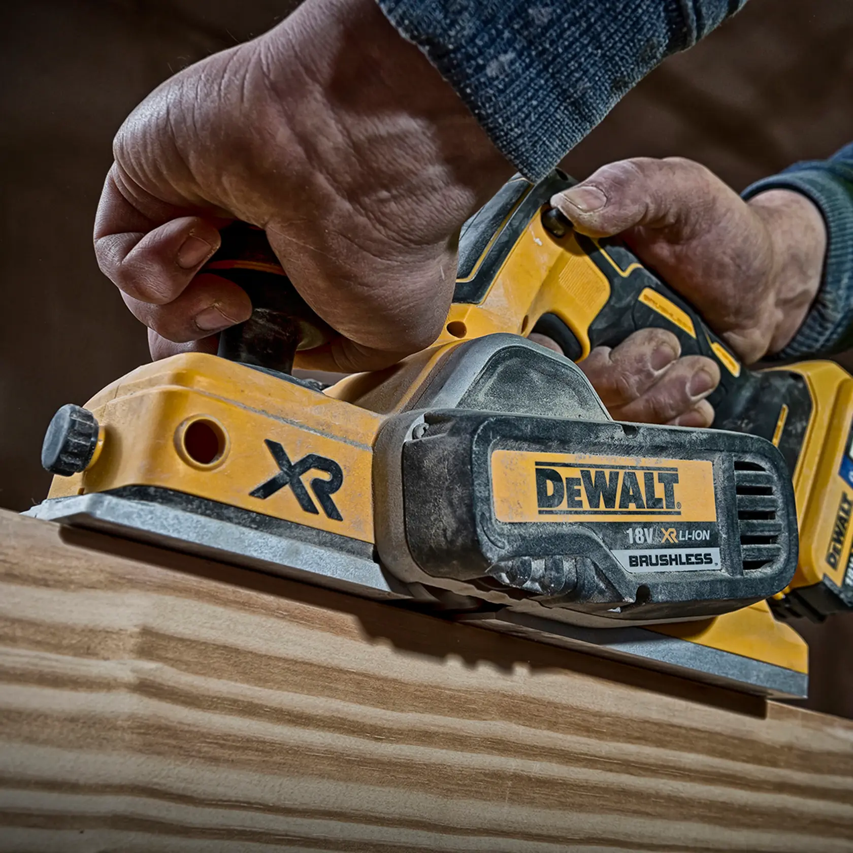 Mano usando cepillo inalámbrico DEWALT DCP580P2 para suavizar madera. Primer plano de la herramienta.