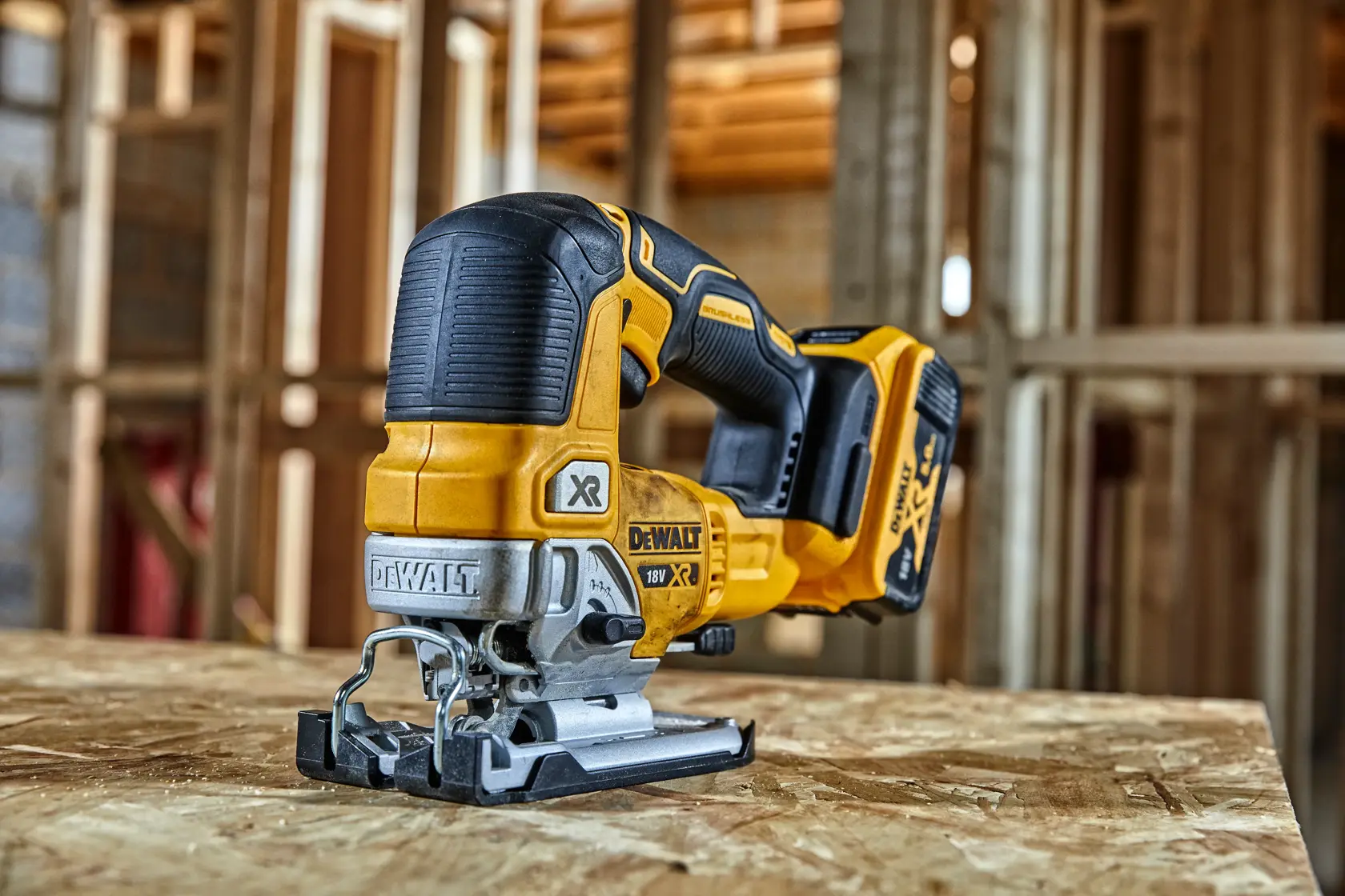 DEWALT DCS334P2 jigsaw used for cutting wood at a construction site by a worker wearing safety gear.