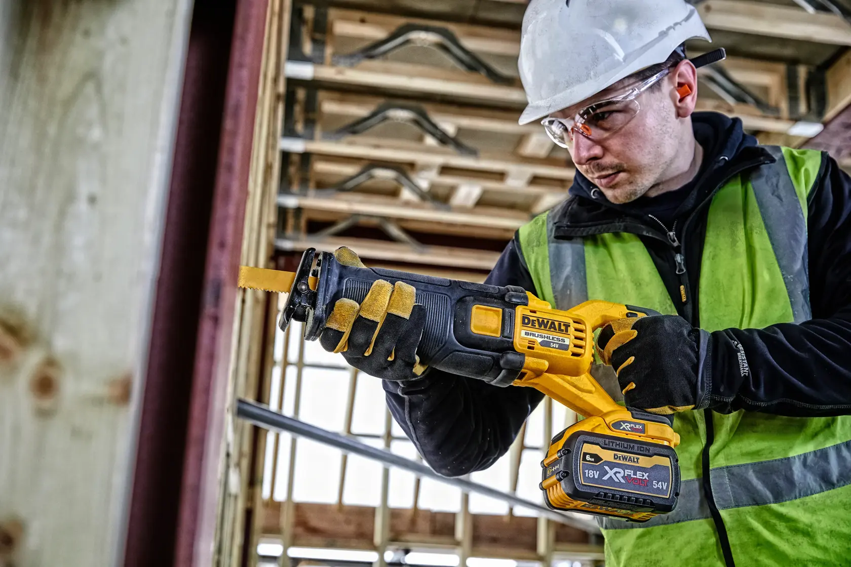 Trabajador usa sierra inalámbrica DEWALT DCS389T2 en obra, con guantes, chaleco y casco.