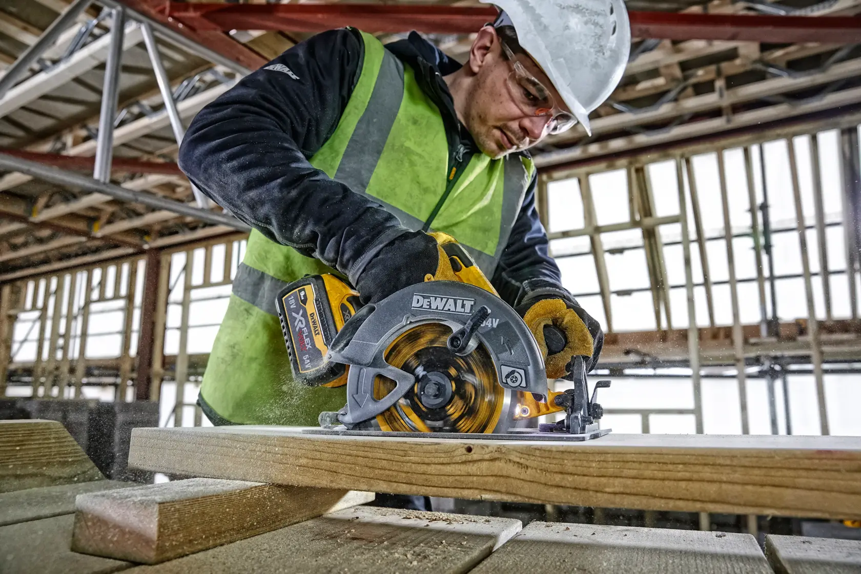 DEWALT DCS578NT Kreissäge schneidet Holz auf Baustelle, Arbeiter mit Sicherheitskleidung.