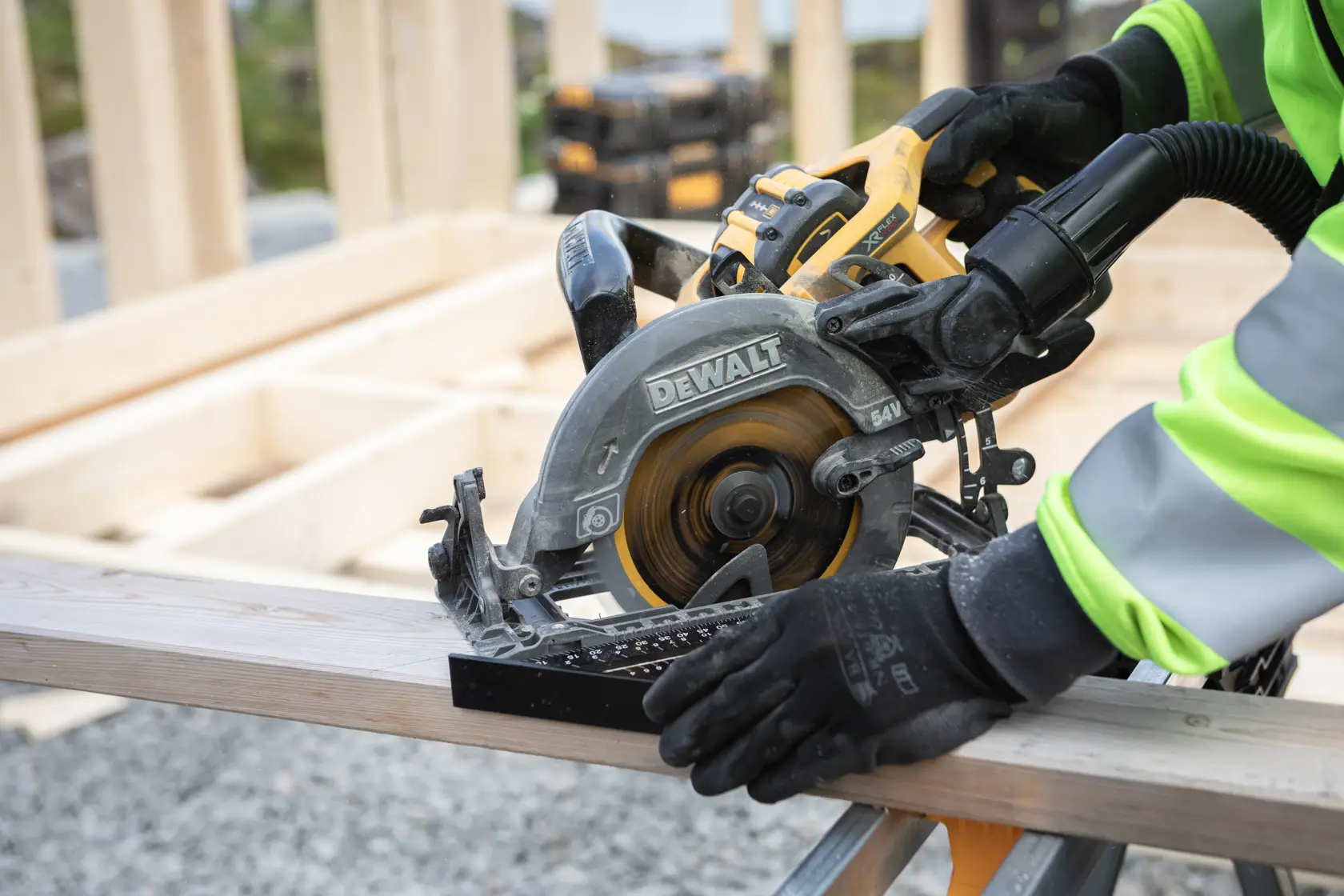 DEWALT circular saw cutting wood, used by person with gloves and safety jacket at a construction site.