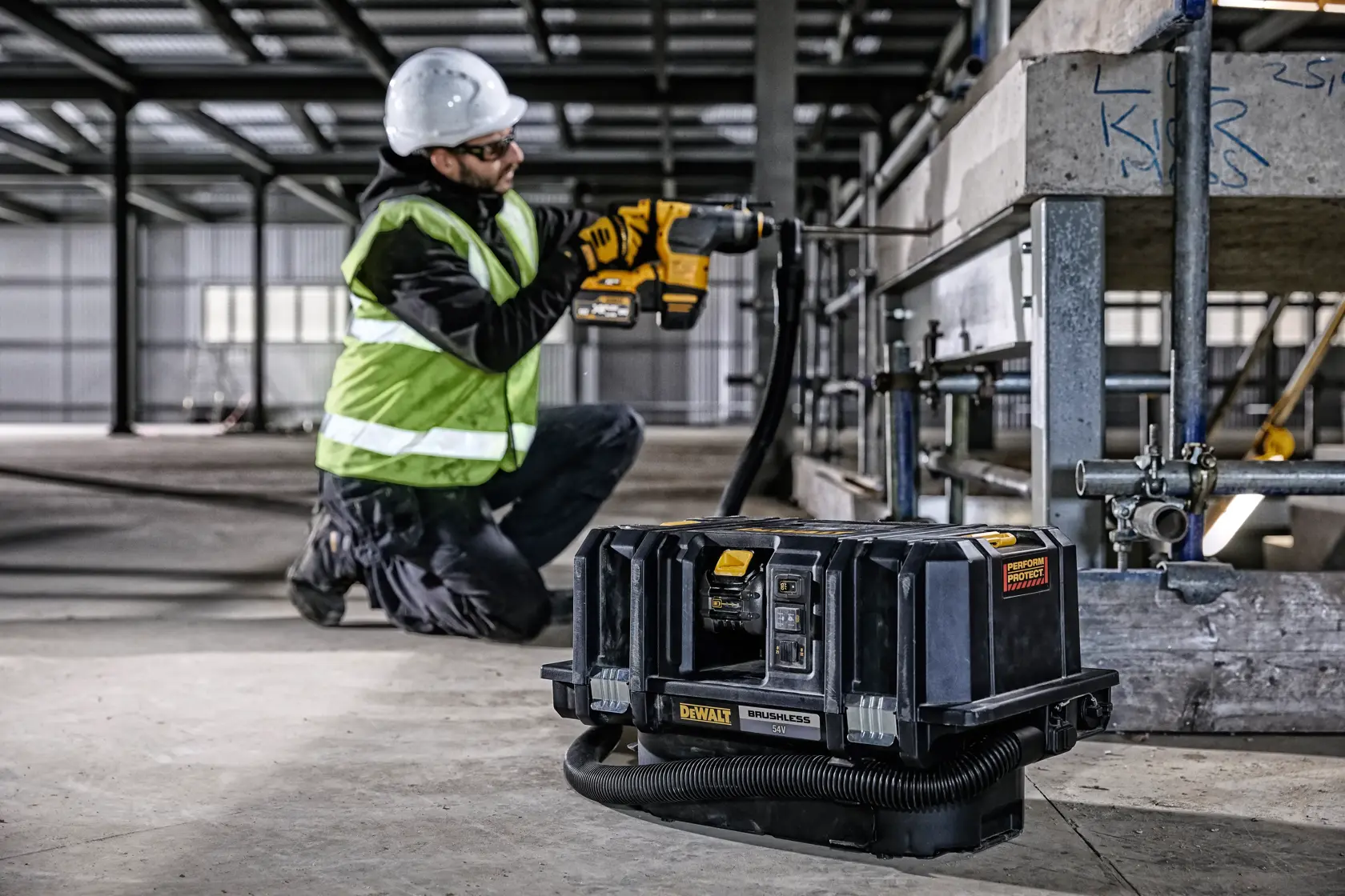 Extractor de polvo DEWALT DCV586MT2 en obra, trabajador con herramienta DEWALT y equipo de seguridad.