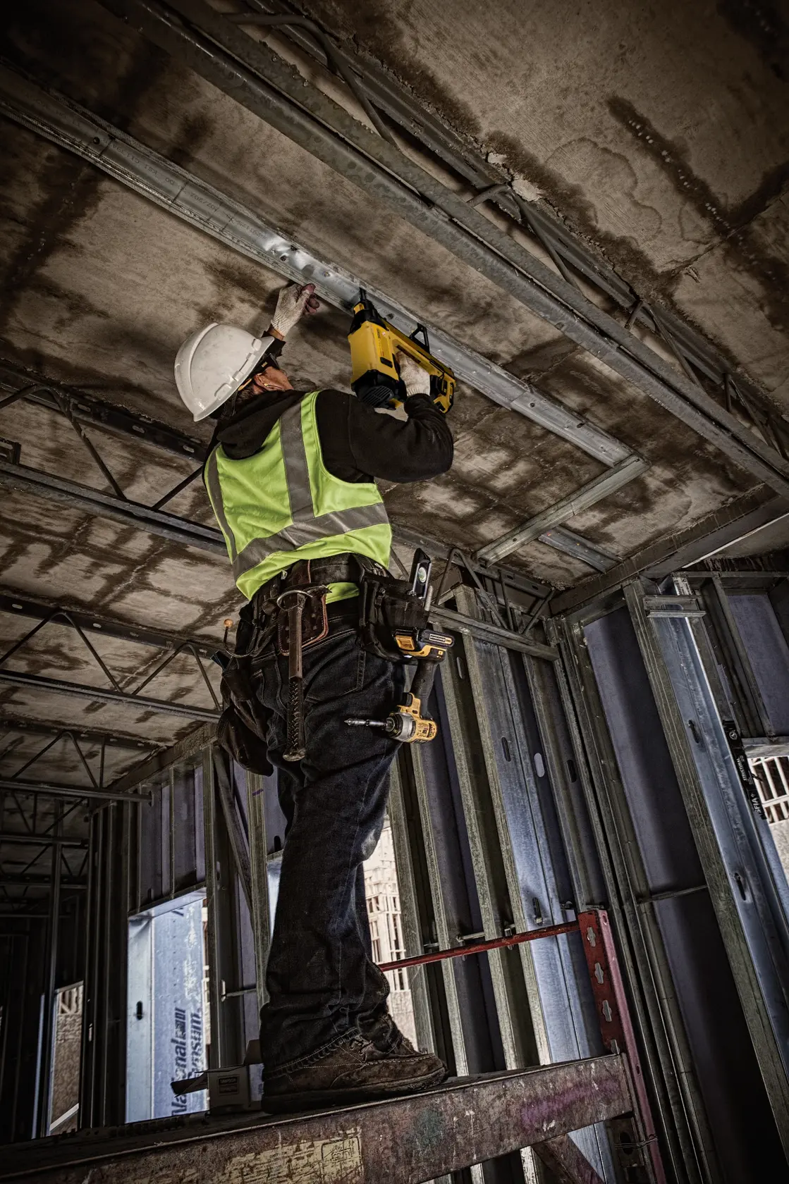 Trabajador usa DEWALT DGN845D1-QW, DGN845D1 herramienta fotográfica en obra. Equipo de seguridad visible.