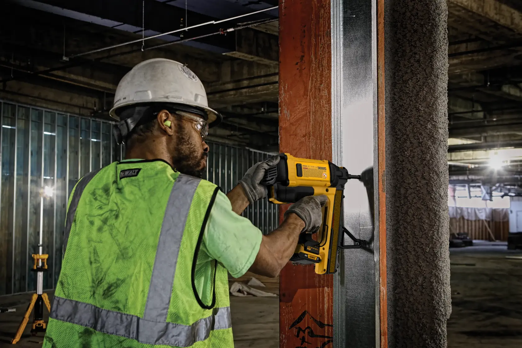 Trabajador usa DEWALT, DGN845D1-QW y DGN845D1, en marco metálico en obra.