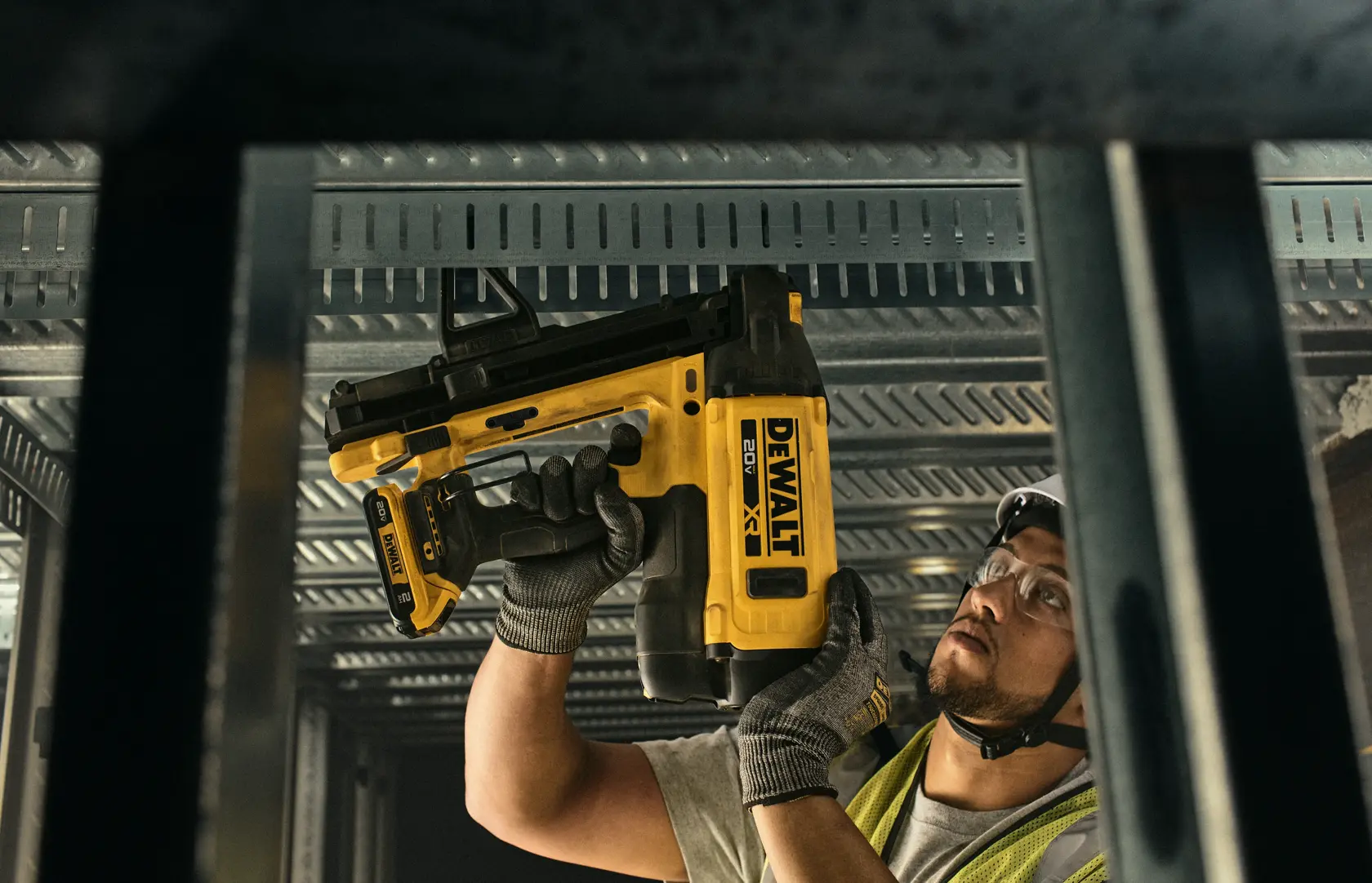 Trabajador con DEWALT DGN845D1-QW, DGN845D1 en techo. Categoría fotografía. Rostro desenfocado.