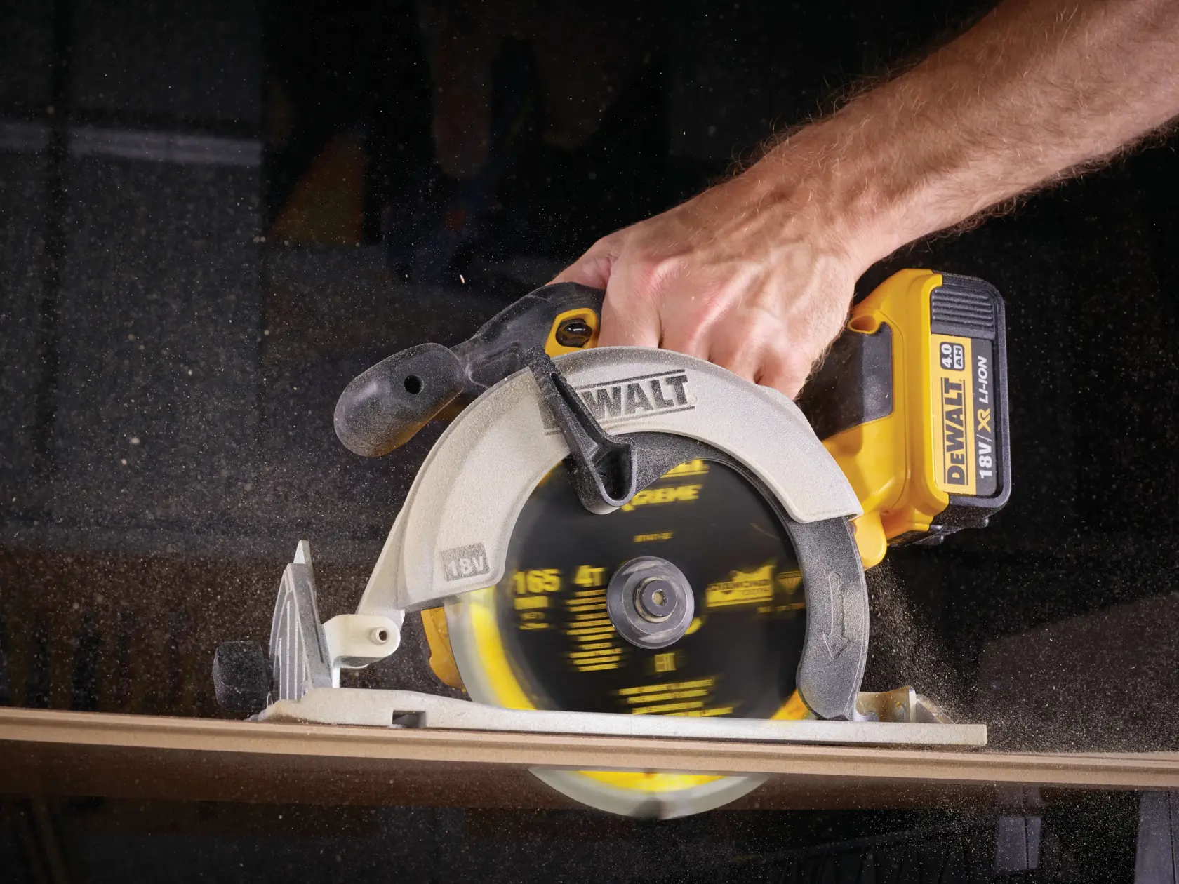 A DEWALT cordless circular saw cutting wood, held by a person, with sawdust flying.