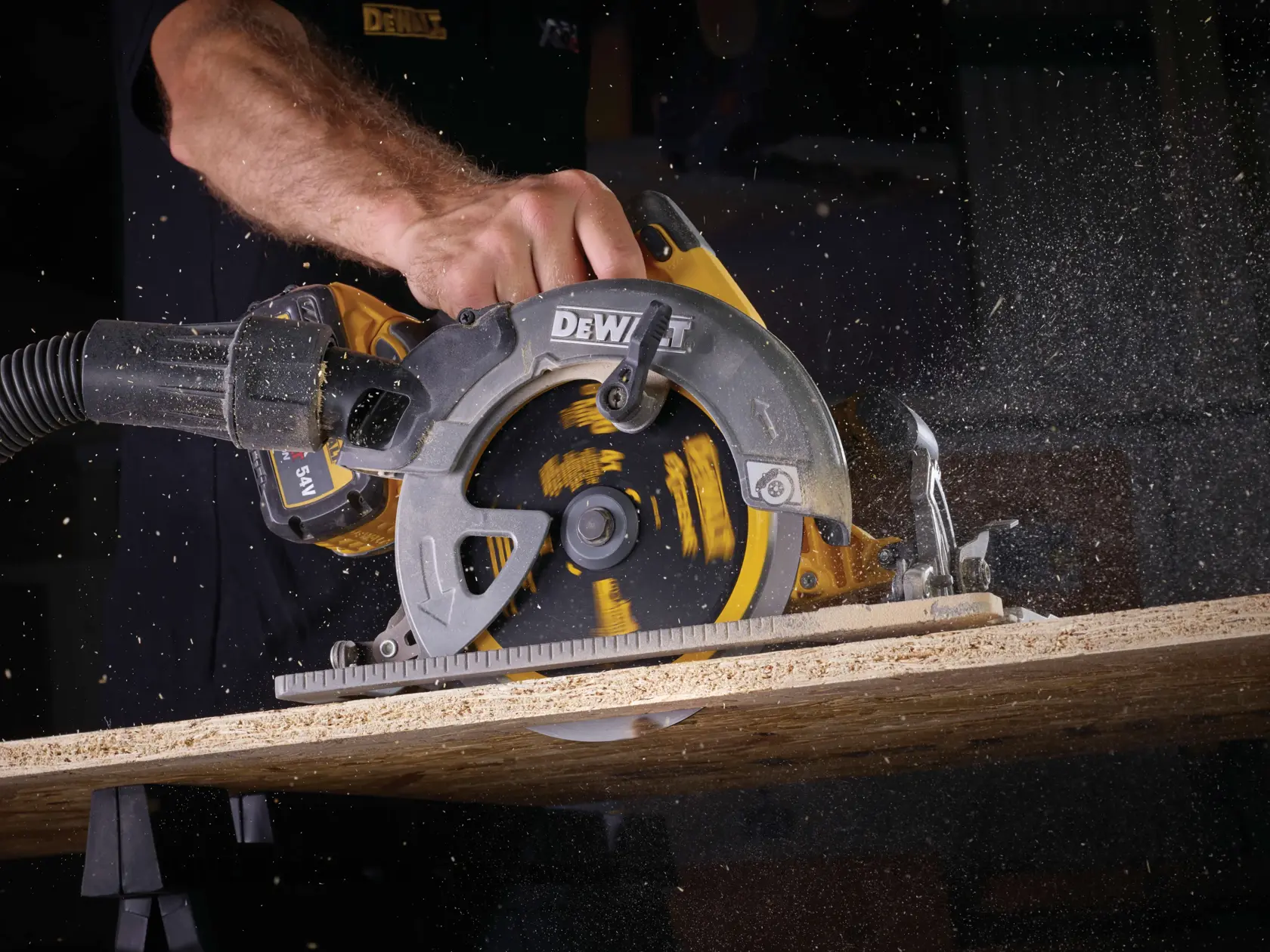 DEWALT circular saw cutting wood, generating sawdust, operator's hand visible in action.