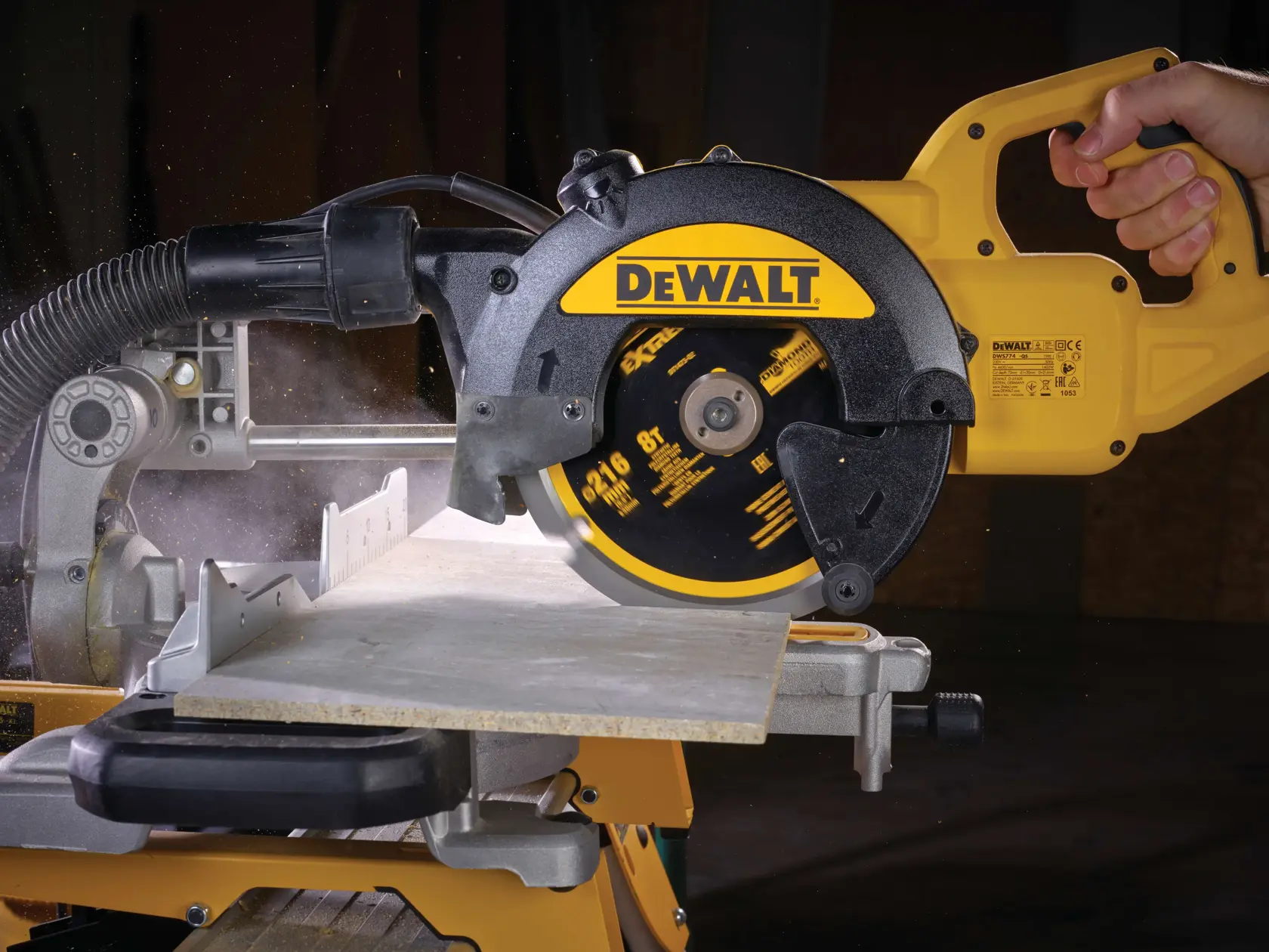 DEWALT circular saw cutting a piece of wood, held by a hand, showing dust and action.