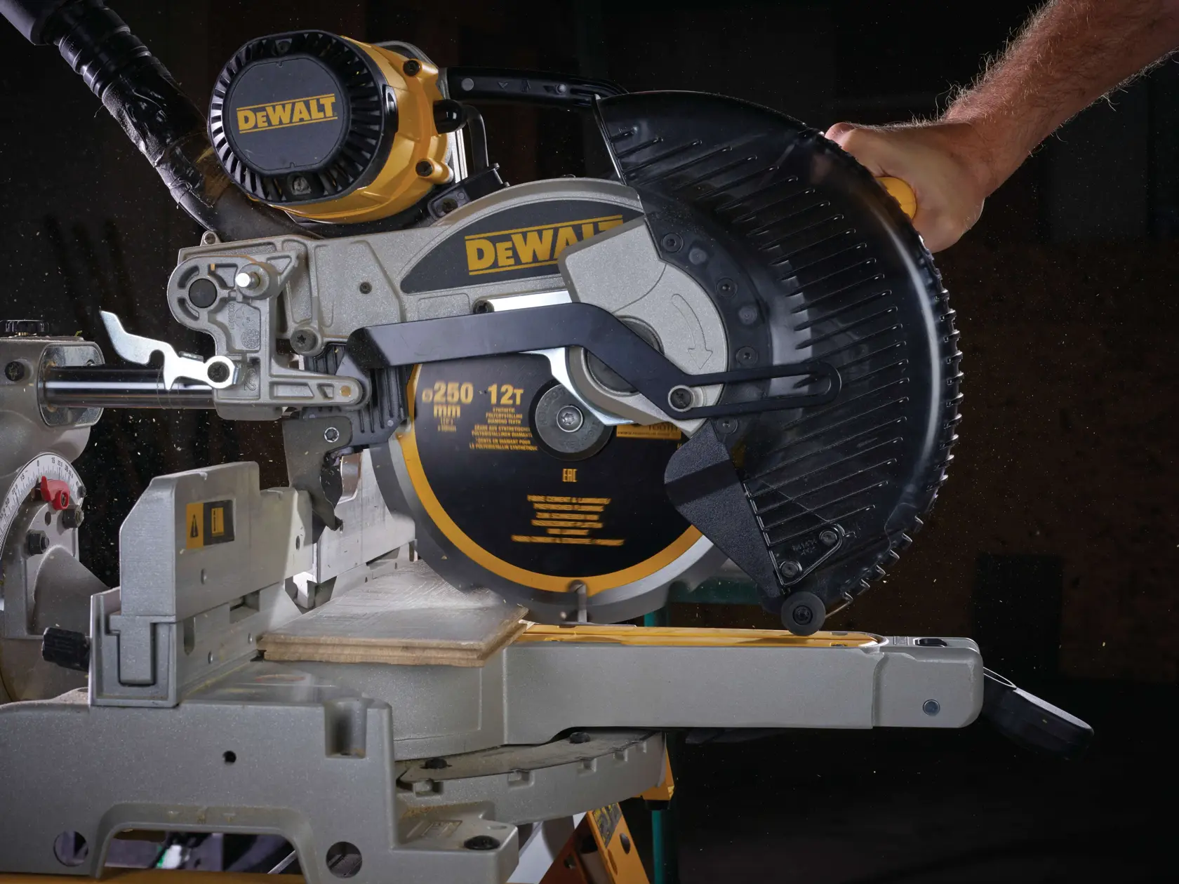 DEWALT mitre saw cutting wood, close-up of blade and guard in operation.
