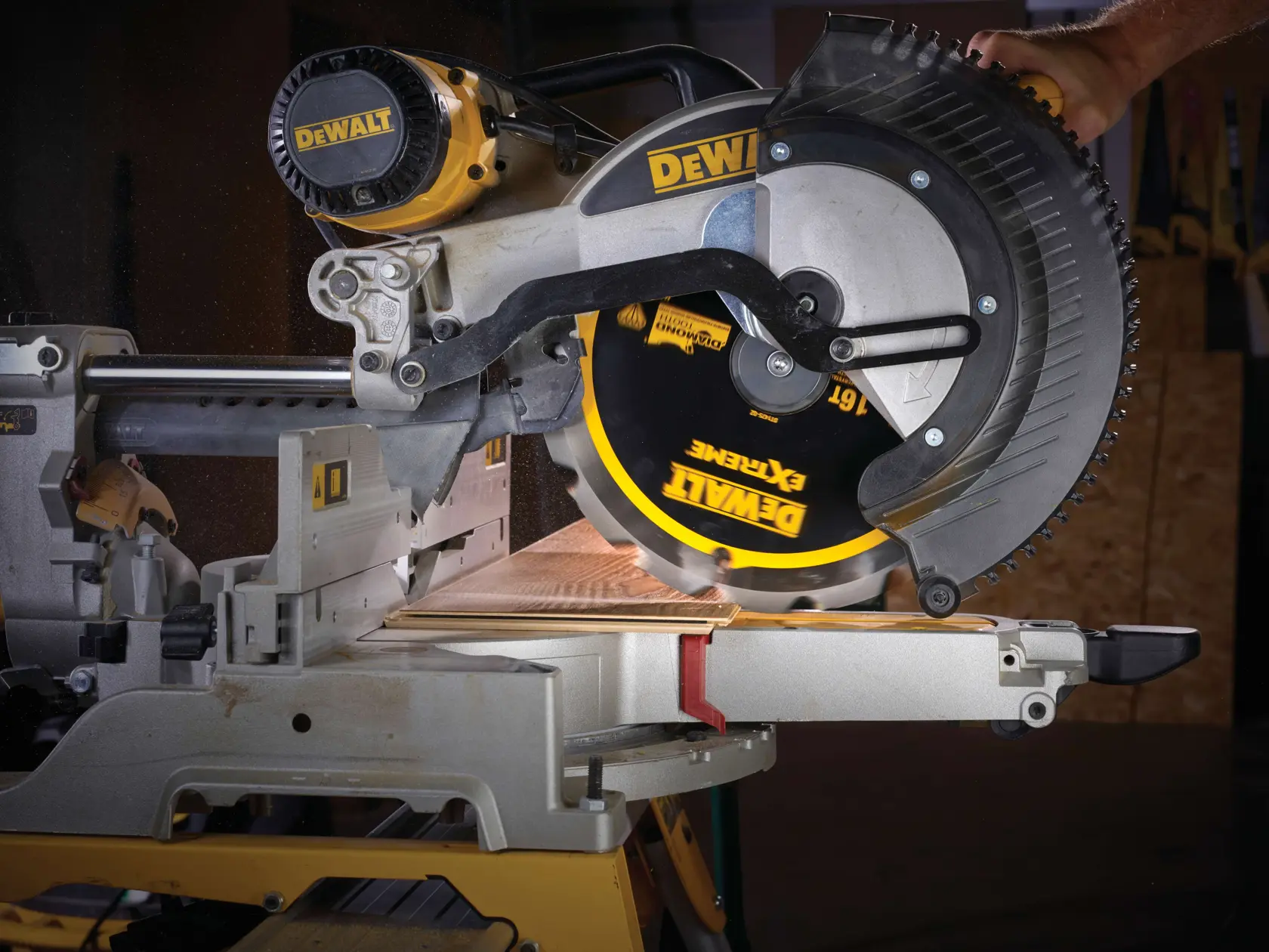 DEWALT circular saw cutting wood, close-up of blade and work area on a miter saw in action in workshop setting.