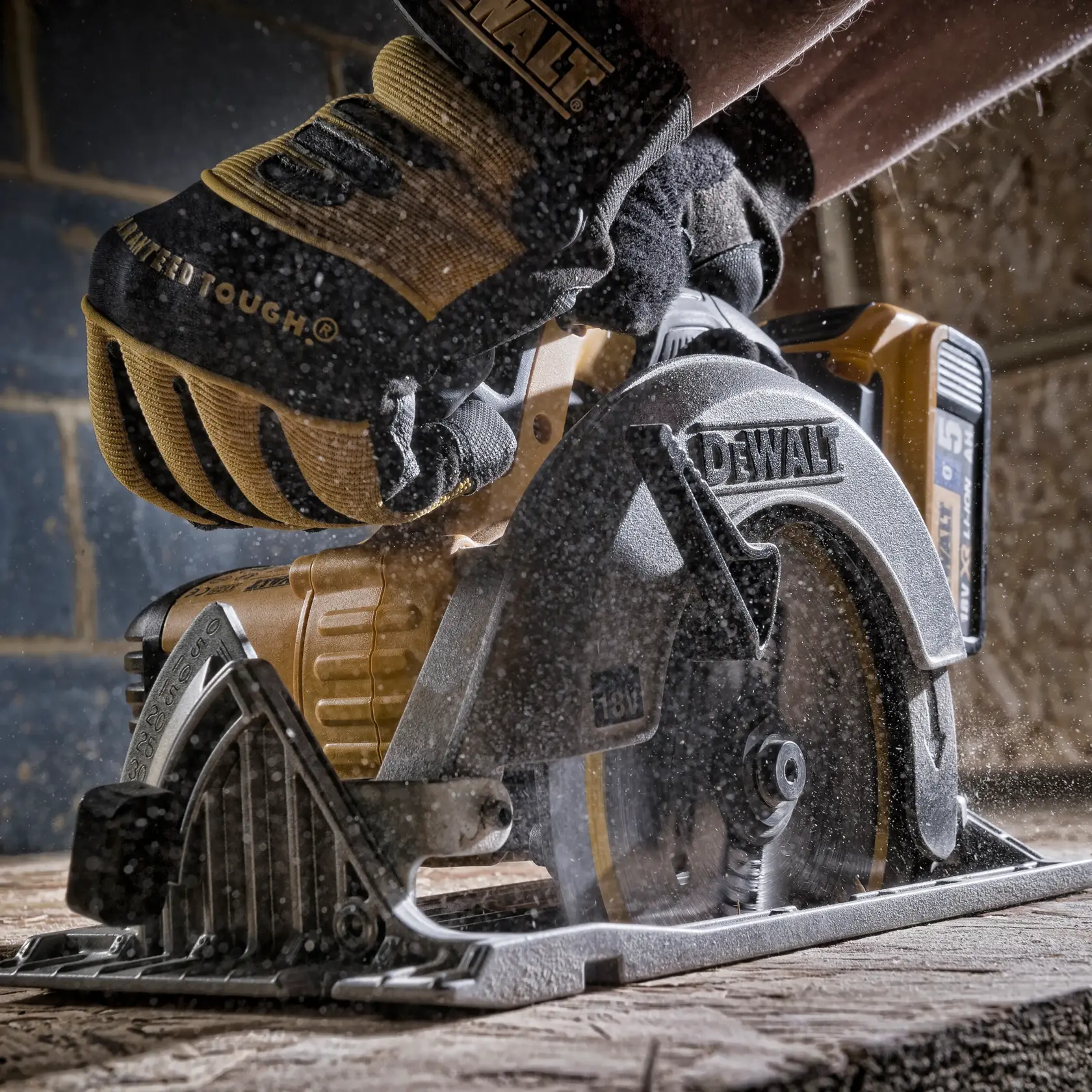 Gloved hand operating a DEWALT circular saw, cutting wood in a dusty workshop environment.