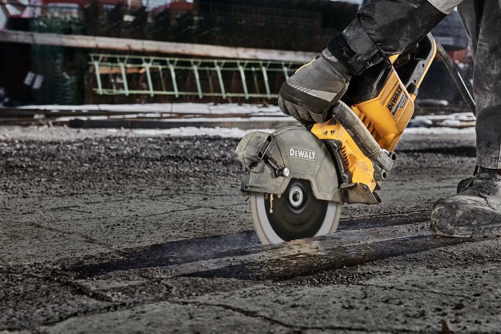 Photo of DEWALT saw cutting asphalt; SKU DT20466-QZ, DT20466. Worker with gloves using power tool outdoors.