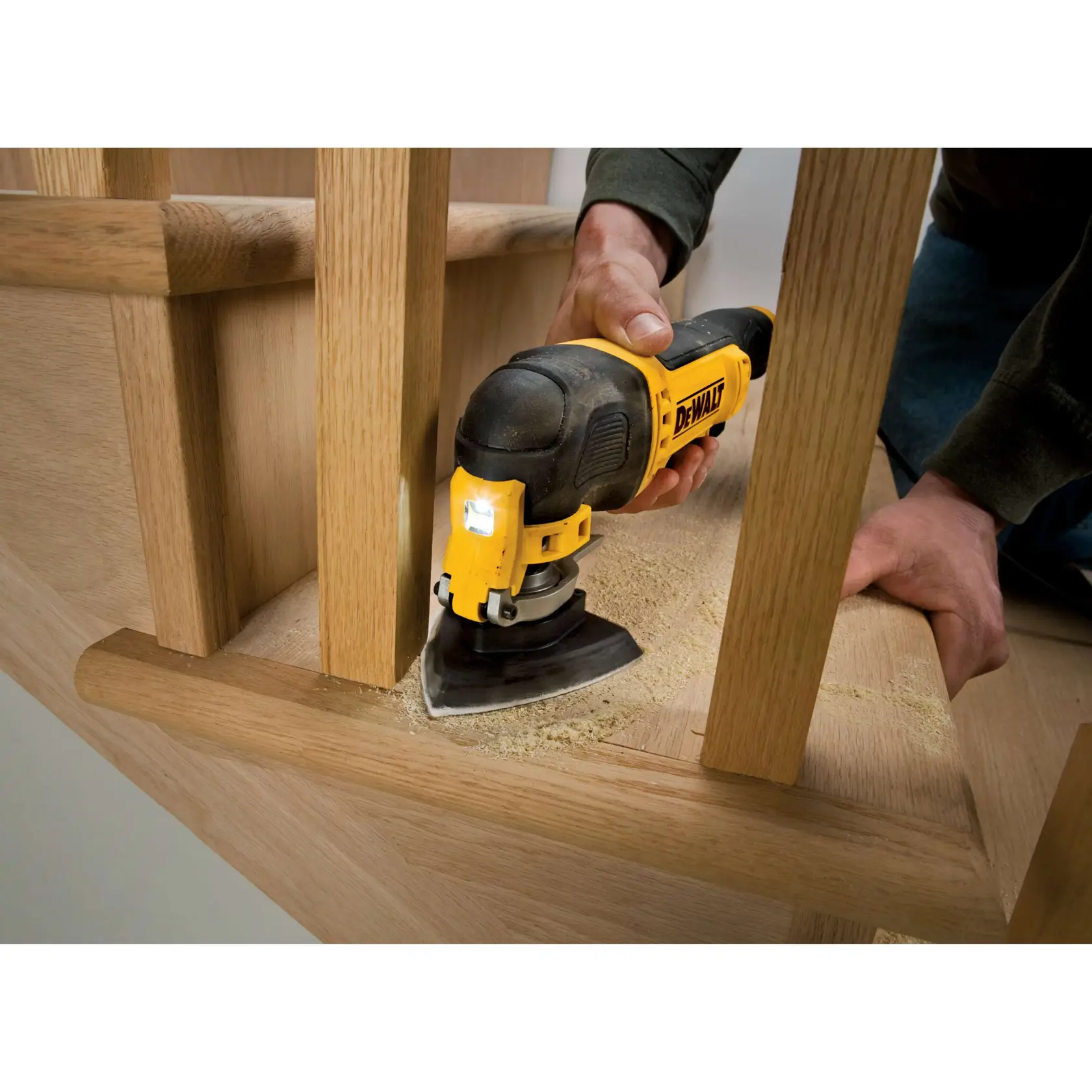 DEWALT sander used to sand wood stairs, creating smooth surfaces and sawdust in a tight corner.
