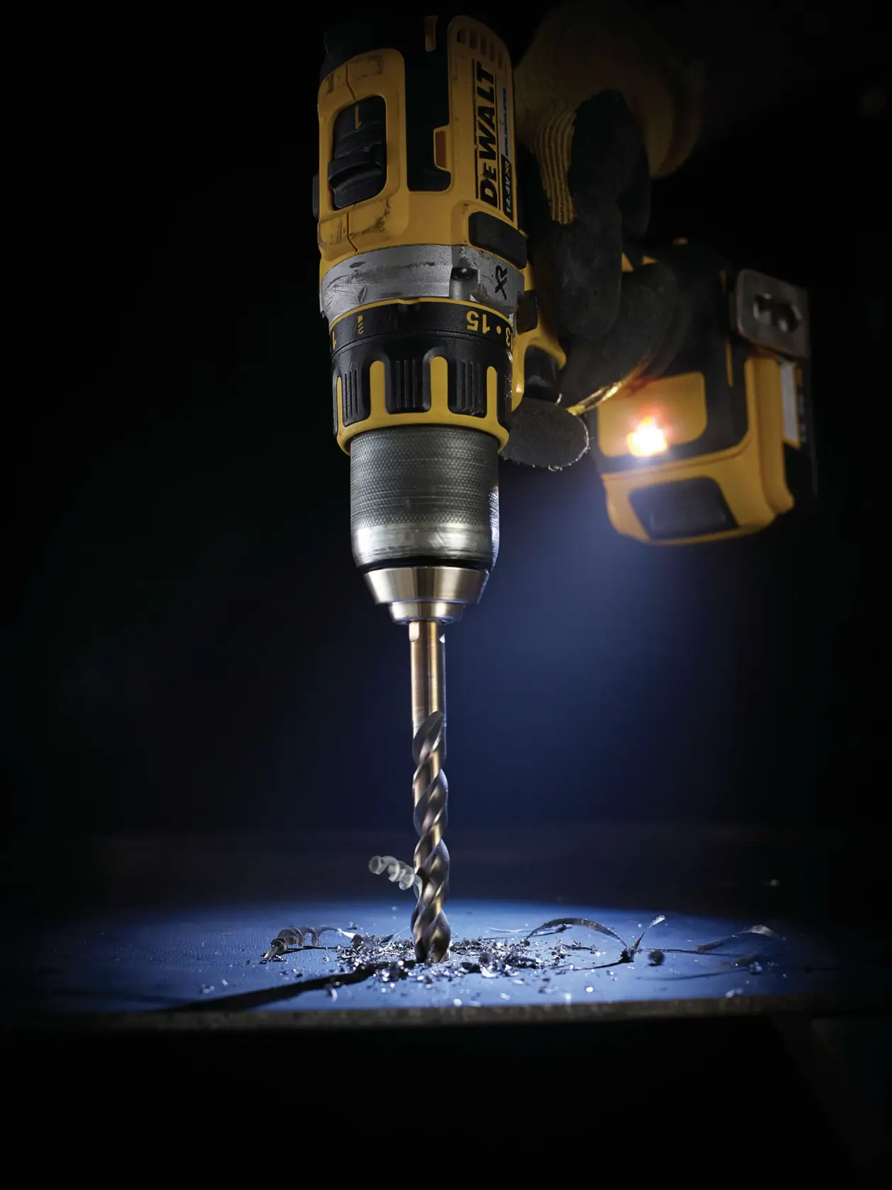 DEWALT drill with DT5546 drill bit making a hole in metal, with metal shavings visible under the drill.