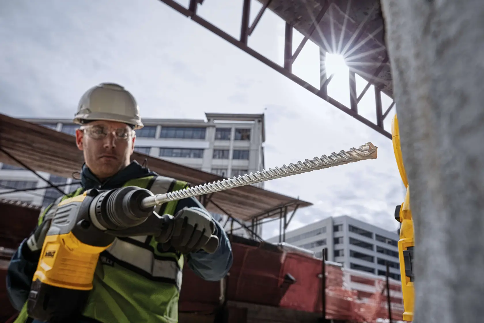 Photo of worker using DEWALT drill bit DT60816, construction site background, close-up view.