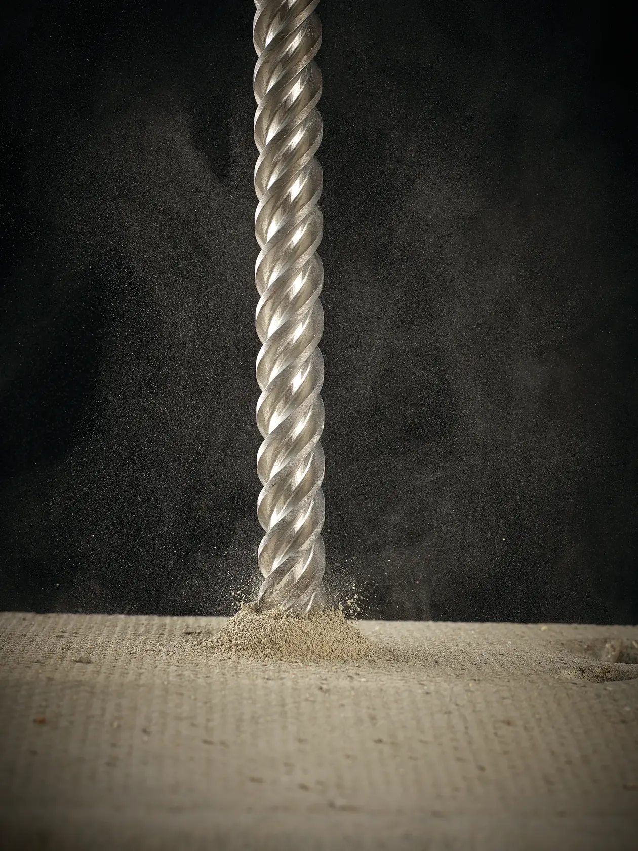 Photo of DEWALT DT60822 drill bit penetrating concrete, dust spraying, close-up view.