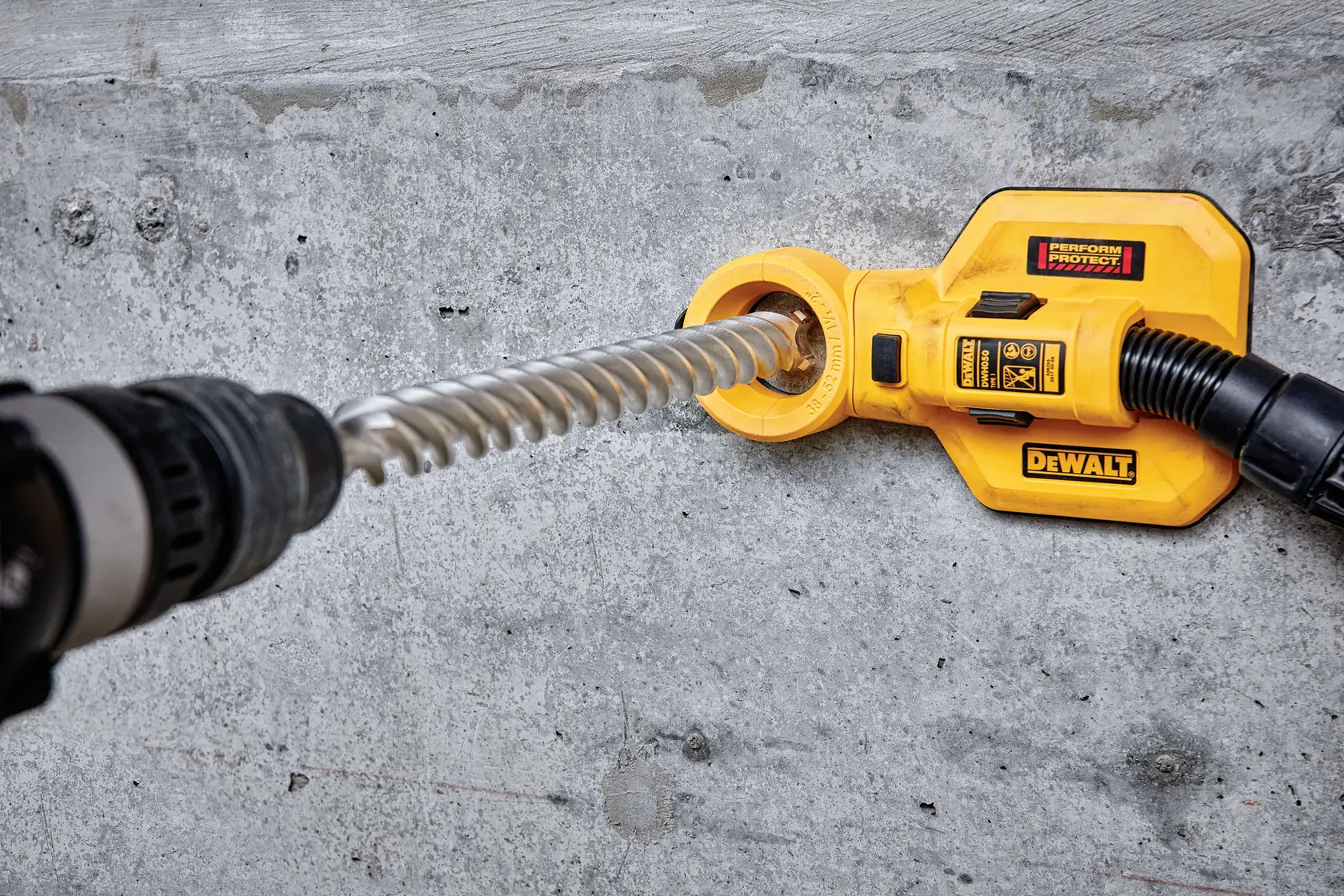 Photo of DEWALT DT60830 dust extractor attached to drill on concrete wall.