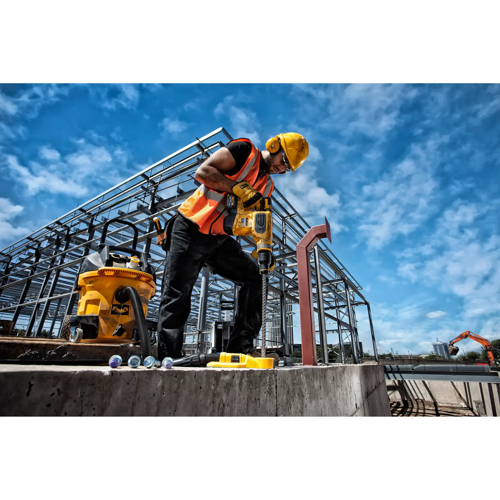Photo of DEWALT DT60839 rotary hammer used by worker in safety gear at construction site, steel frame in background.