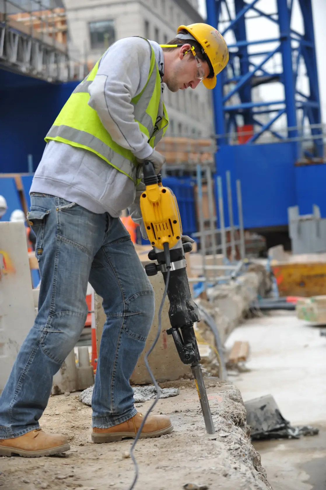 Worker using DEWALT jackhammer DT6929-QZ, DT6929 at construction site, wearing safety gear.