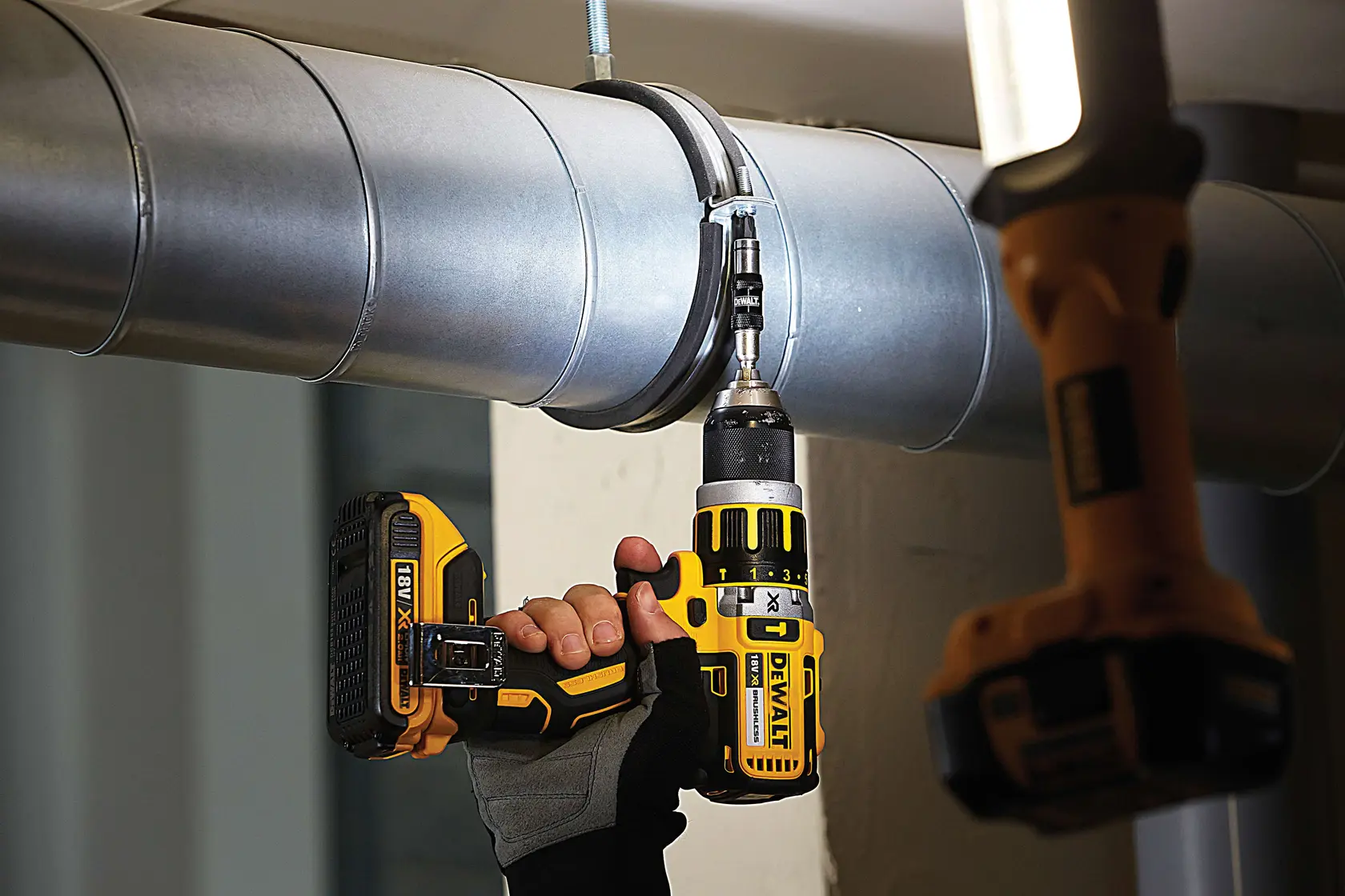 Photo of DEWALT cordless drill DT70518T in use on a metal duct by a gloved hand.