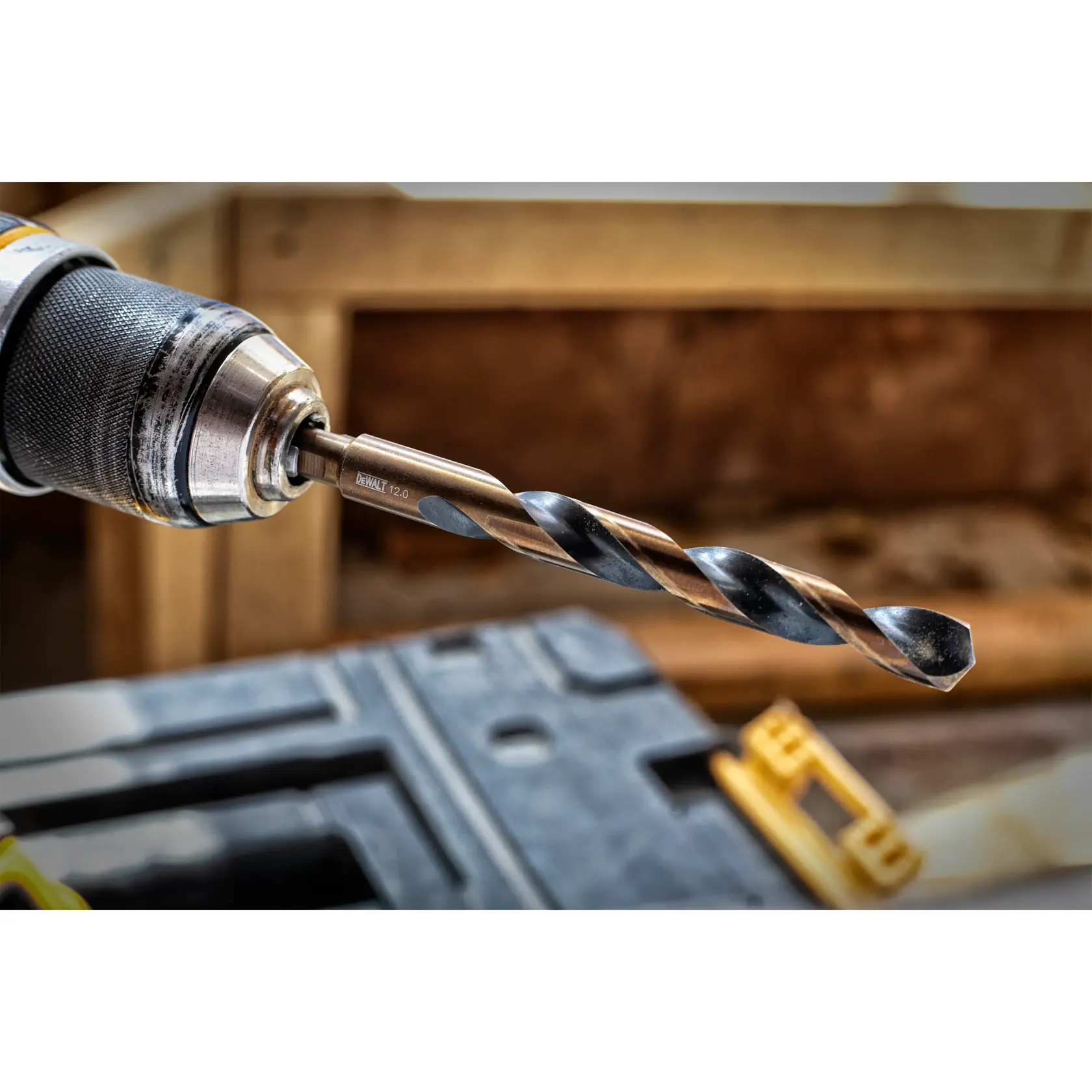 Close-up of a DEWALT drill bit attached to a power drill, with a toolbox visible in the background.