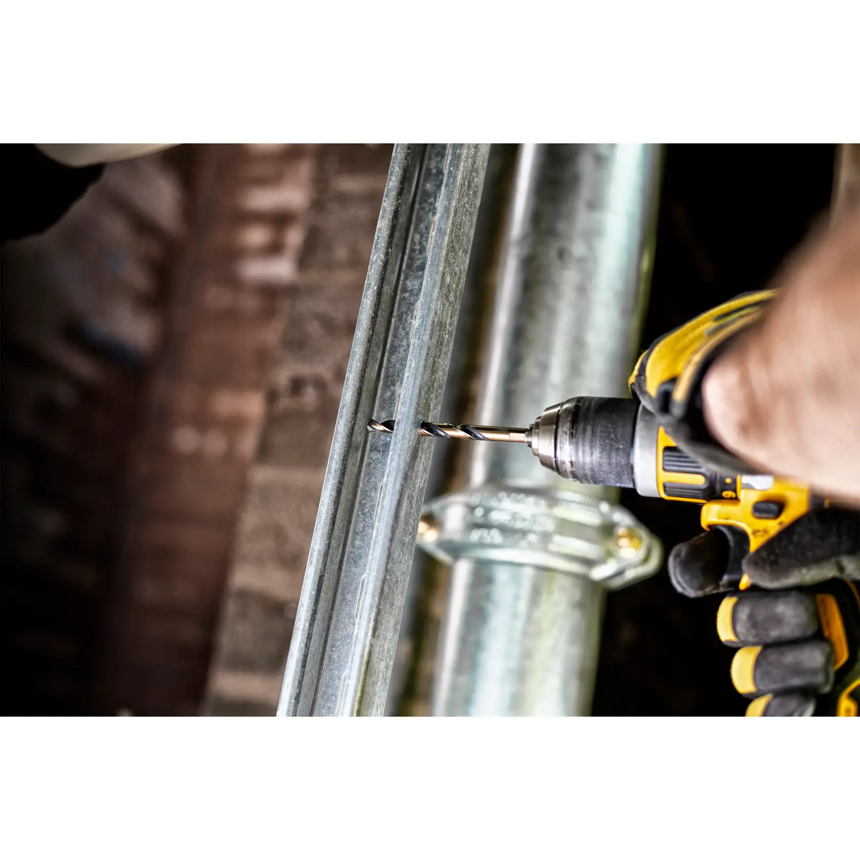 Person uses DEWALT drill to make a hole in a metal beam while wearing work gloves.